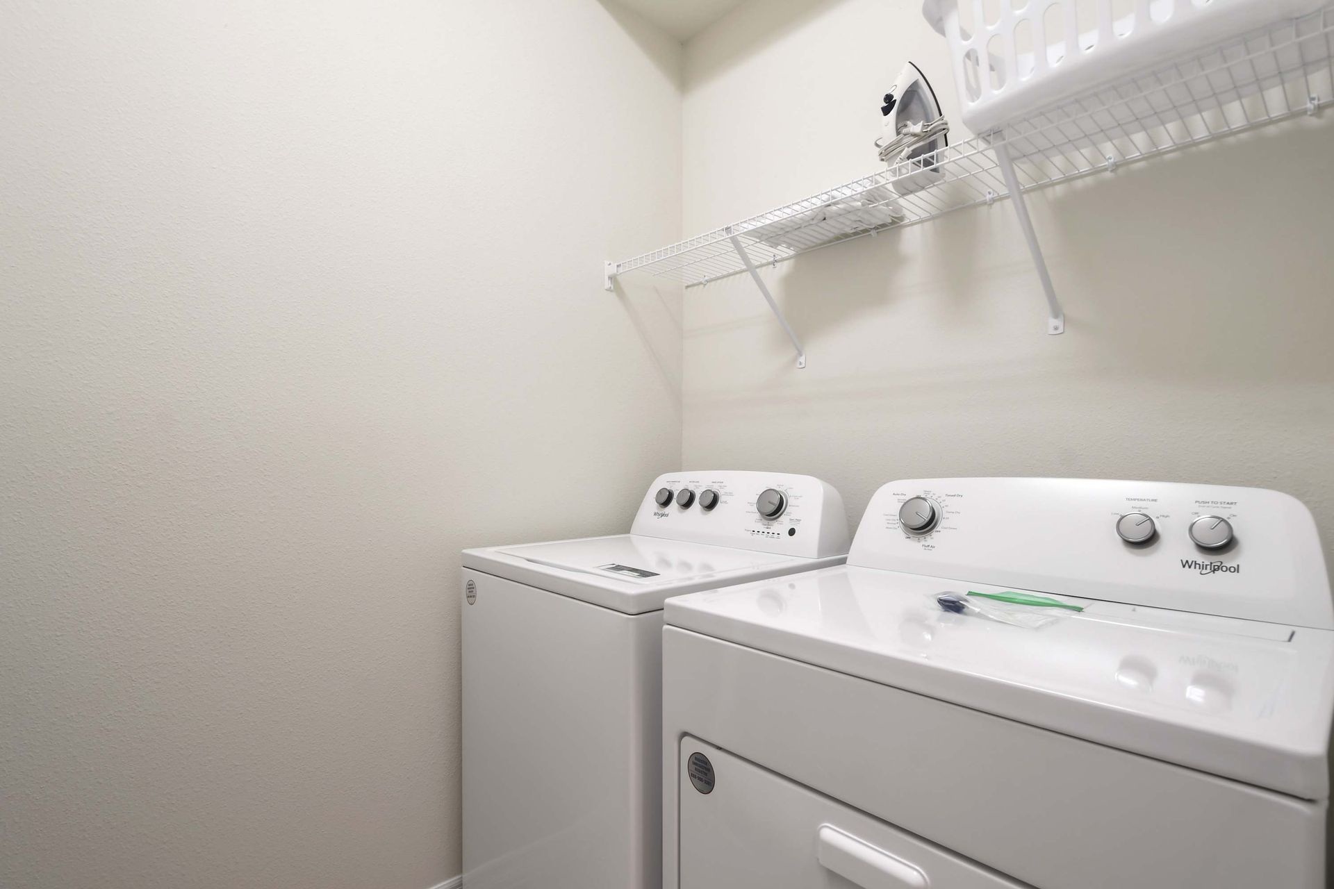 Dedicated laundry room with full-size washer, dryer, and convenient shelving above.