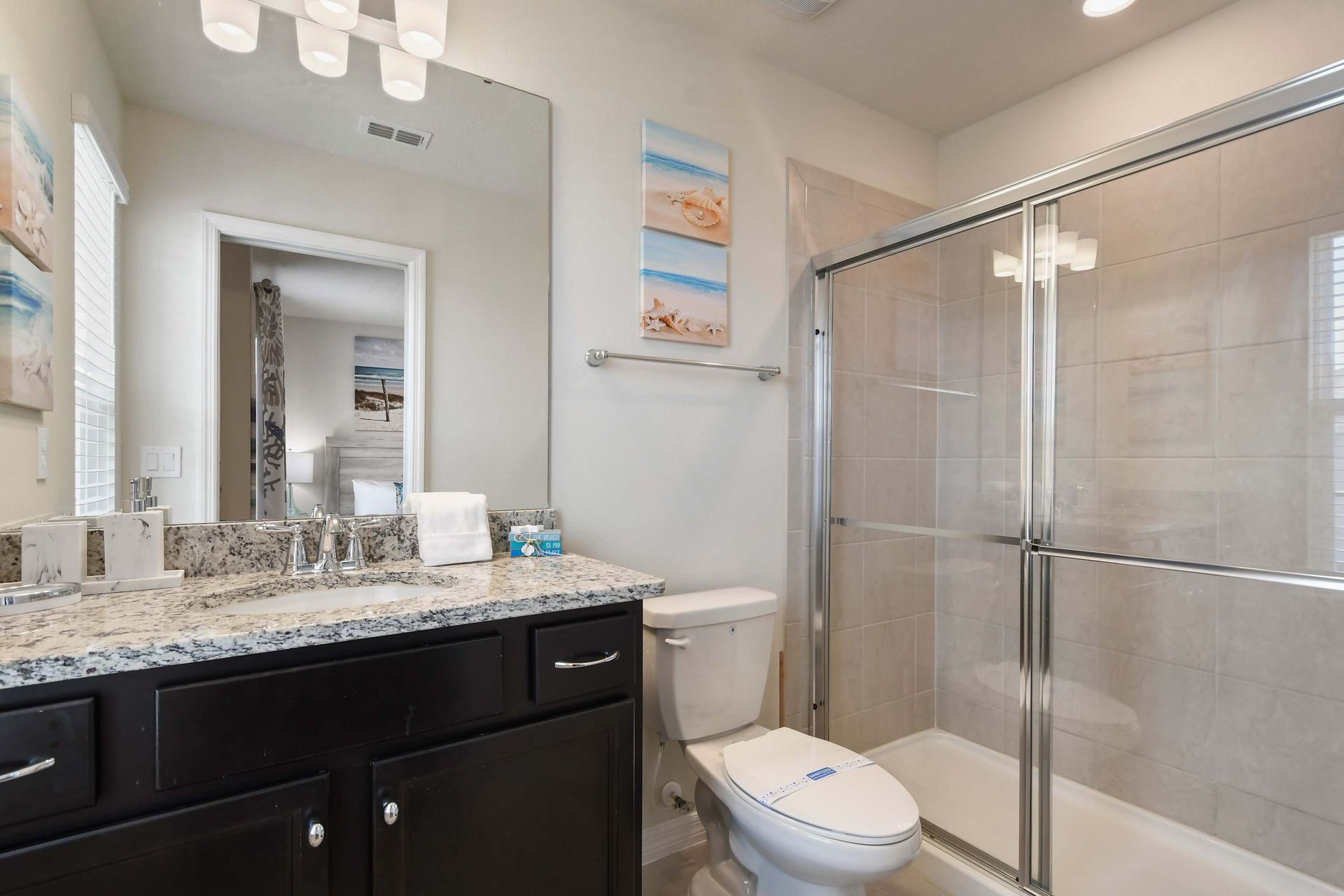 Coastal-inspired bathroom with granite vanity, walk-in shower, and beachy accents.