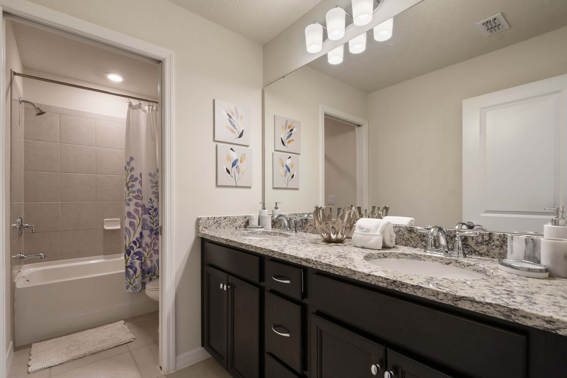 Stylish full bathroom with dual sinks, granite counters, and a tub-shower combo.