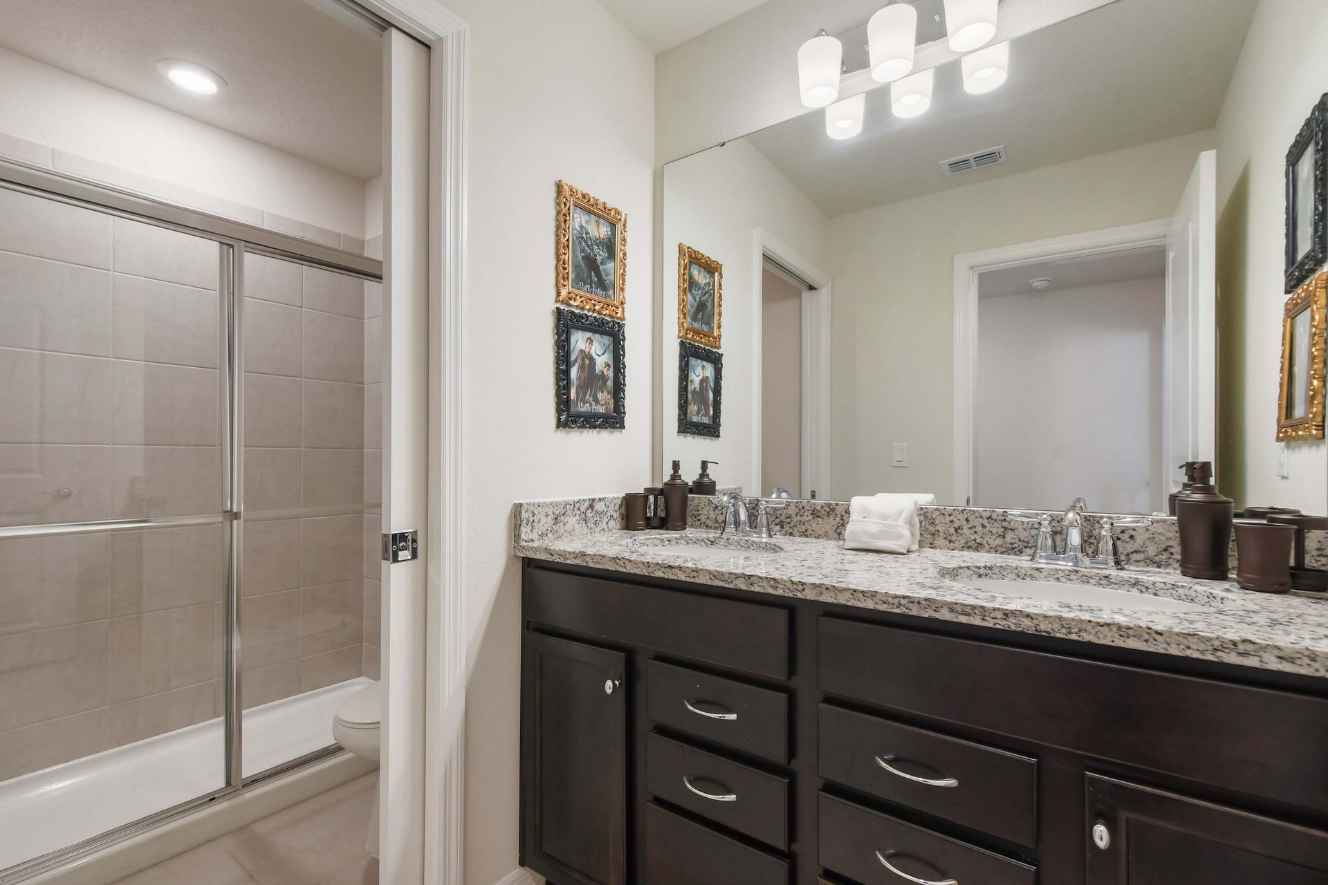Elegant bathroom with double sinks, granite counters, and a walk-in glass shower.