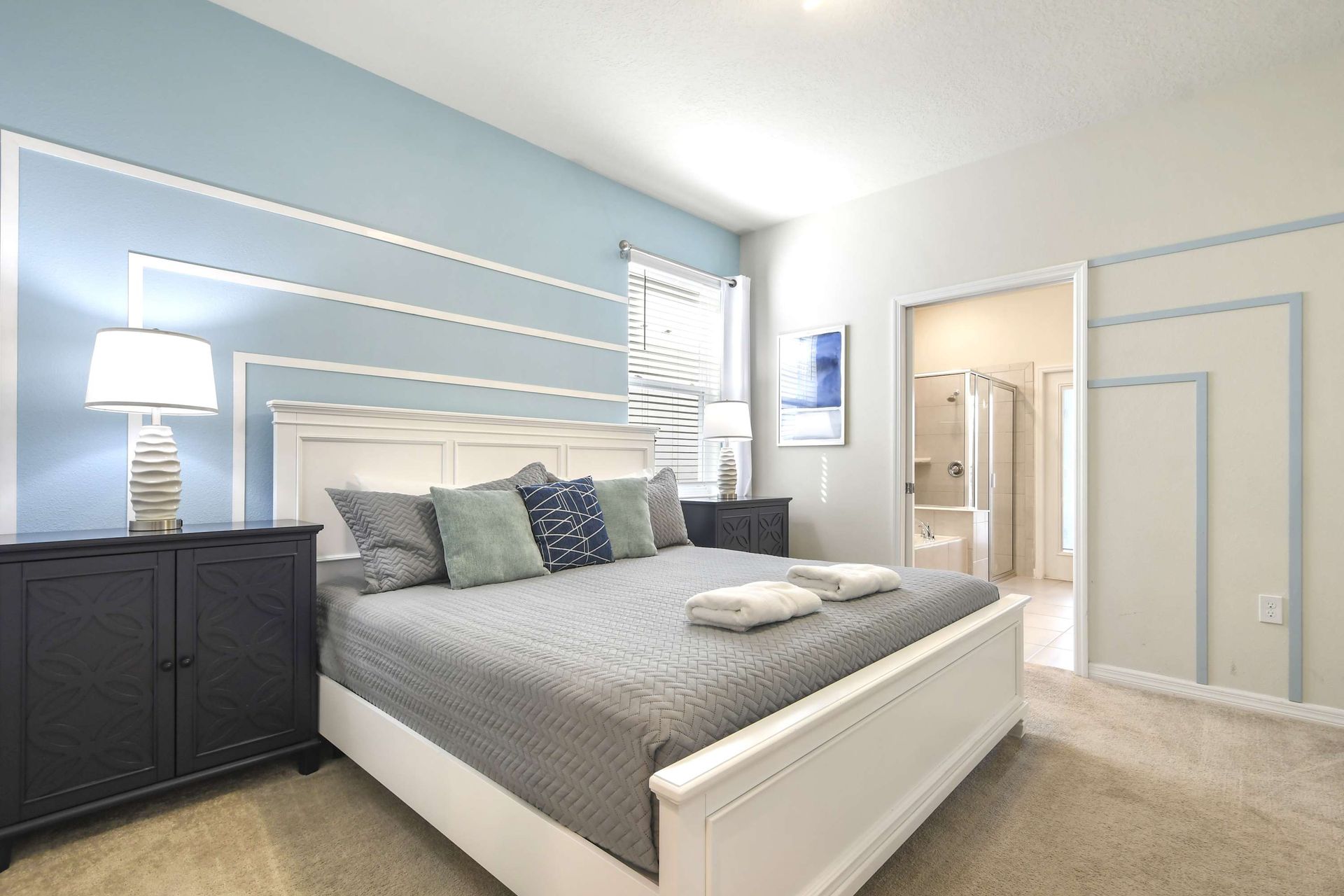 Modern king suite with accent wall, cozy bedding, and private en-suite bathroom.