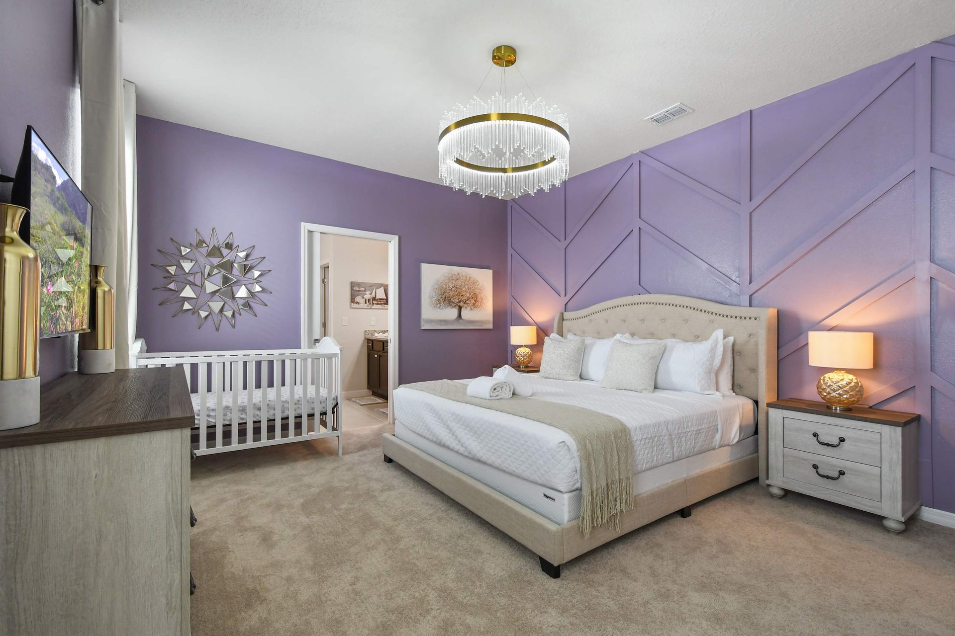 Stylish bedroom with a chic purple accent wall, plush bedding, and a cozy crib.