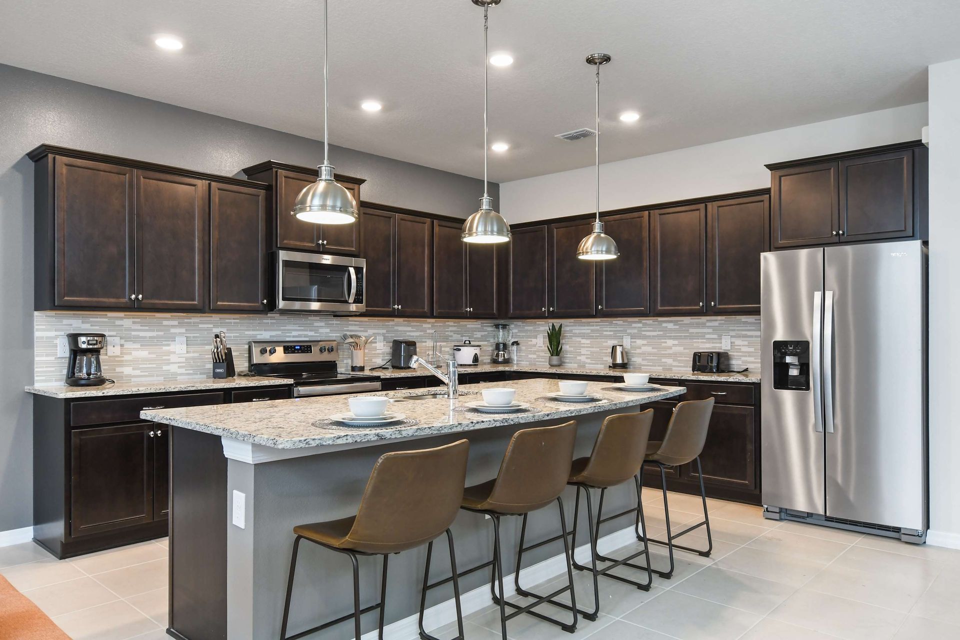 Sleek chef’s kitchen with granite island, stainless steel appliances, and bar seating.