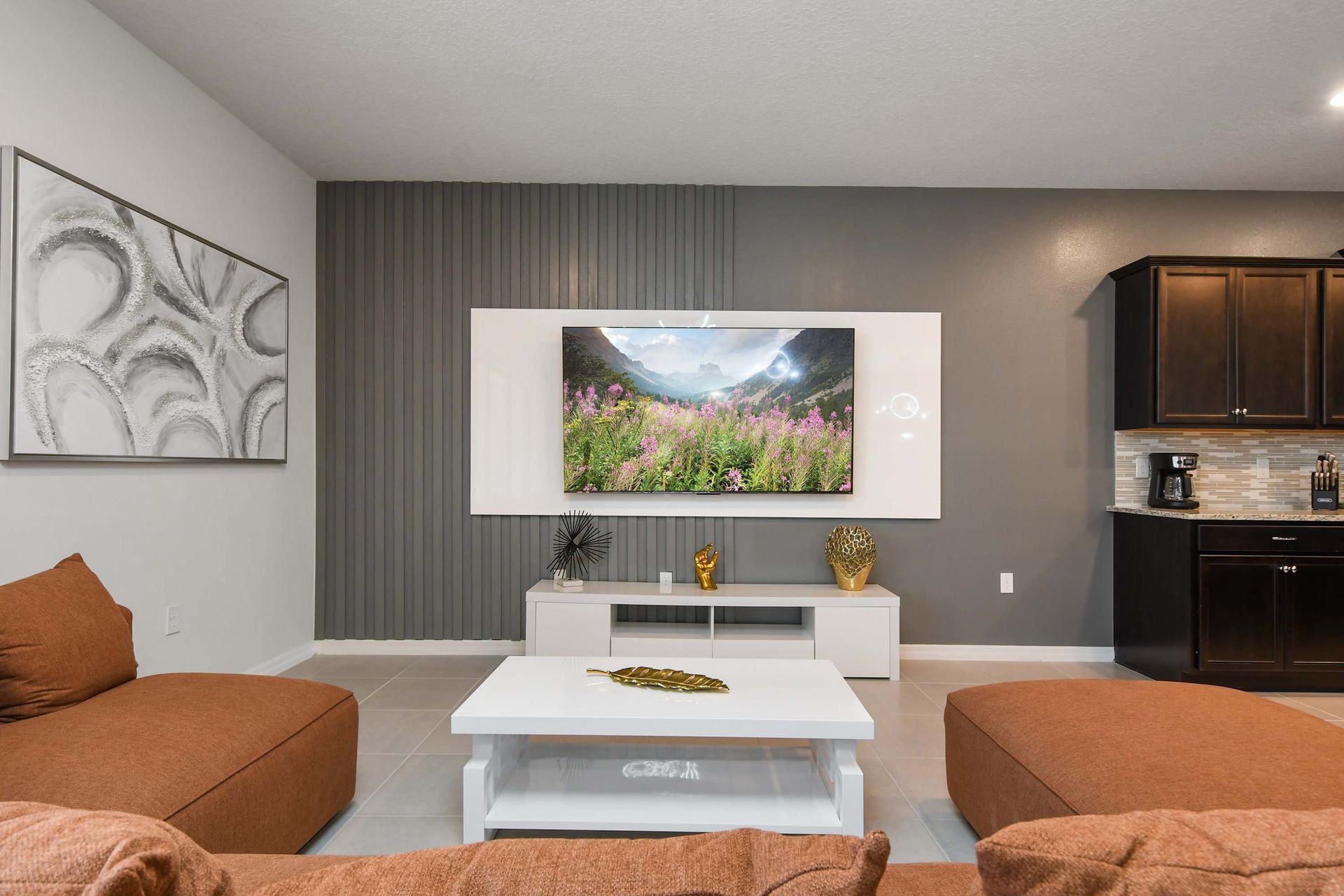 Cozy designer lounge with sleek TV wall, modern art, and elegant decor accents.