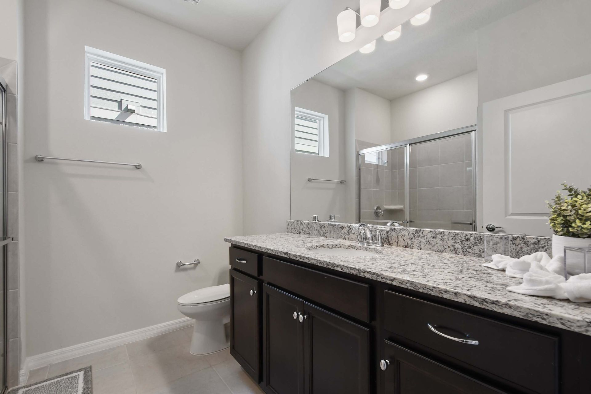 Bright and modern bathroom with a spacious granite countertop and shower.