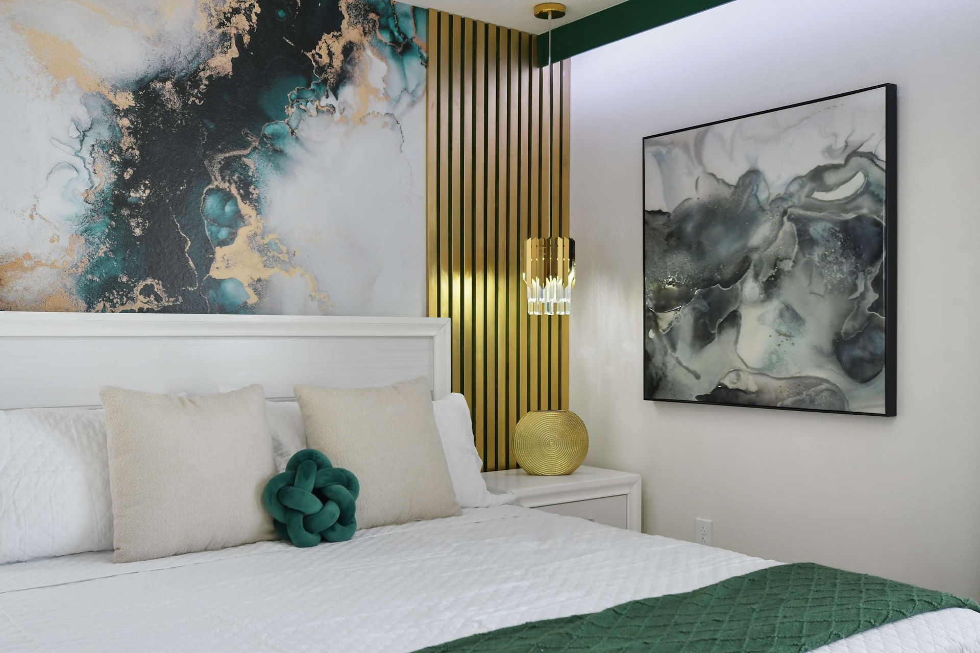 Sophisticated bedroom with emerald and gold accents, modern art, and a plush bed.