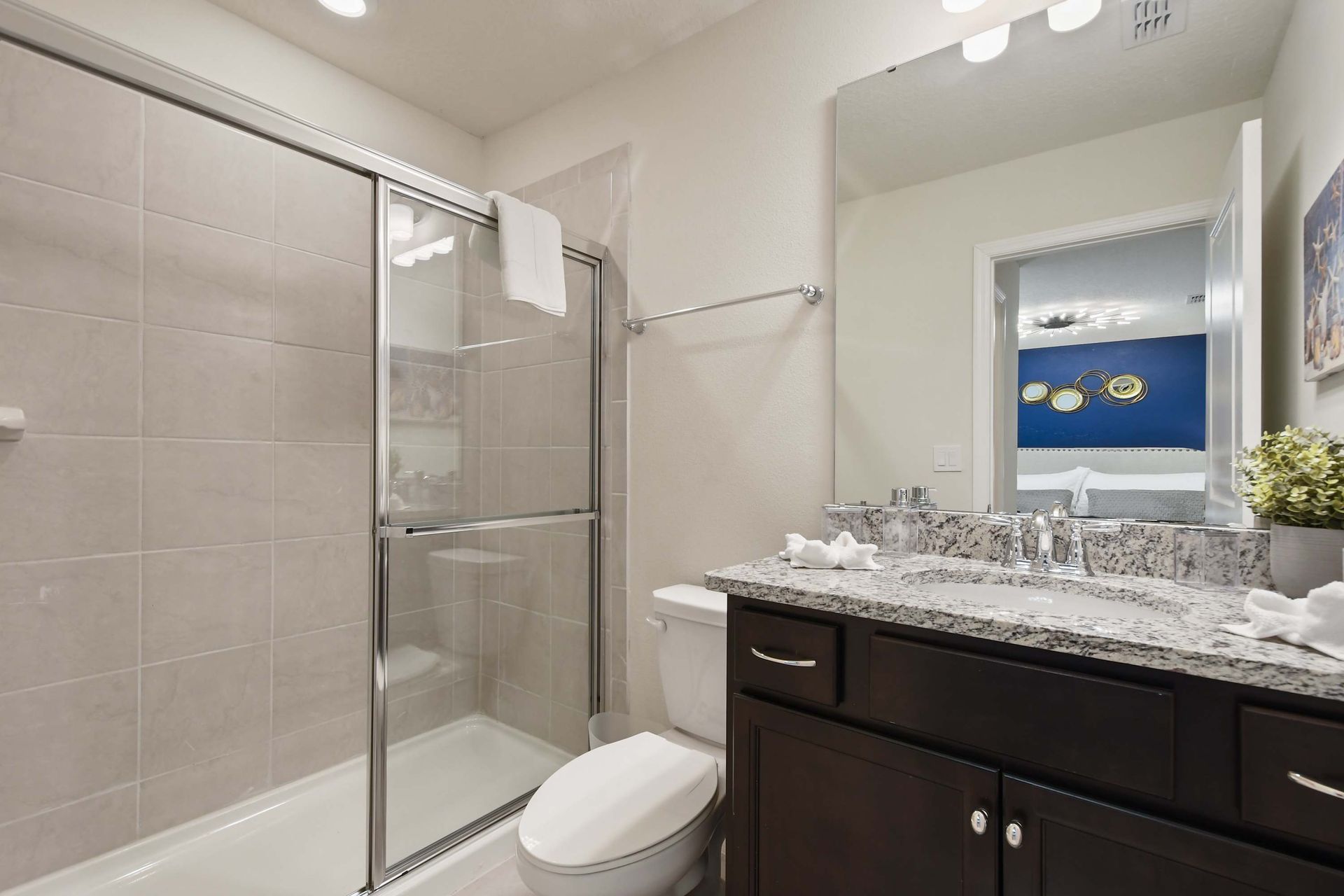 Modern bathroom with granite countertop, spacious shower, and sleek finishes.