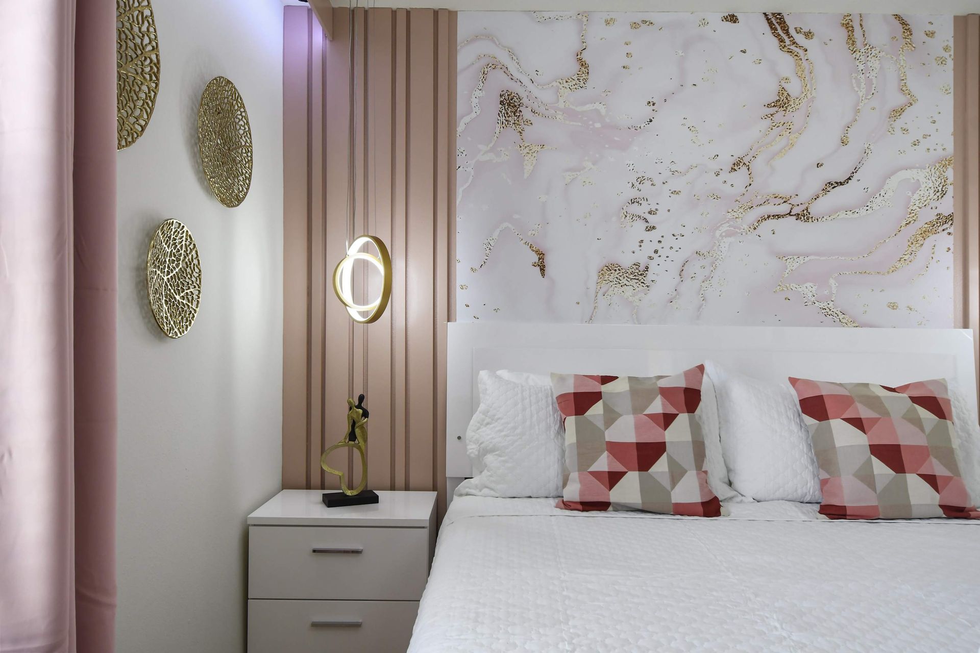 Elegant blush-toned bedroom with geometric accents, gold decor, and modern lighting.