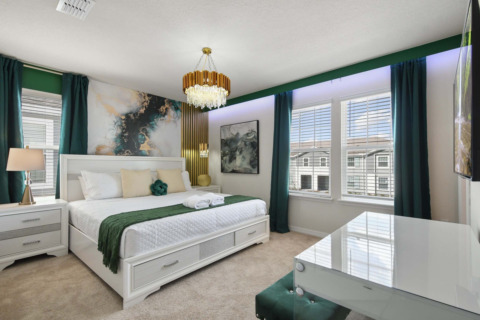 Luxurious bedroom with emerald accents, elegant chandelier, and modern artistic flair.