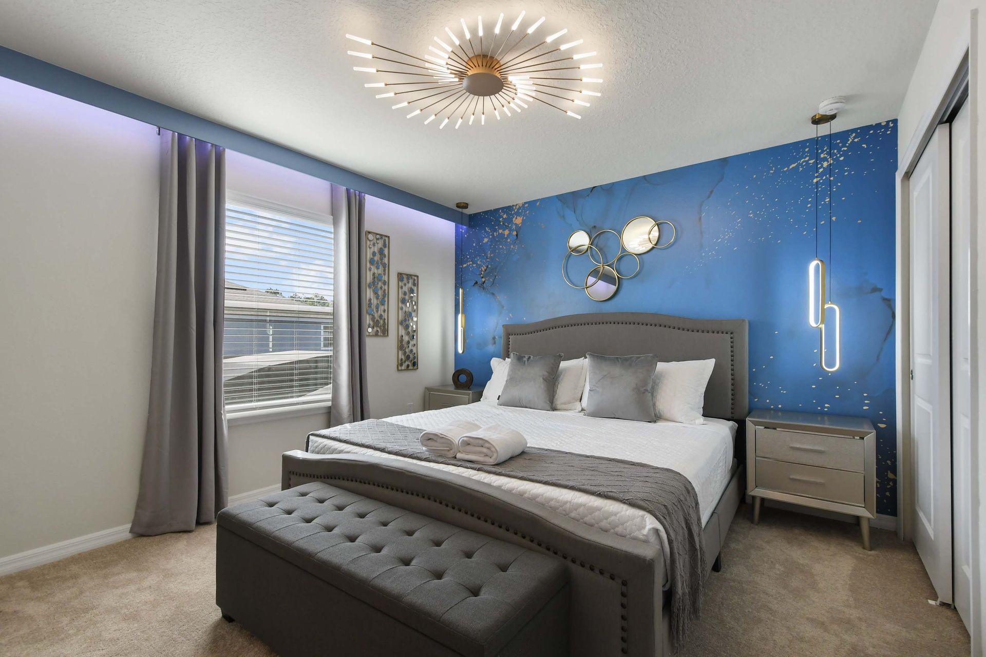 Stylish bedroom with bold blue accent wall, modern lighting, and plush king bed.