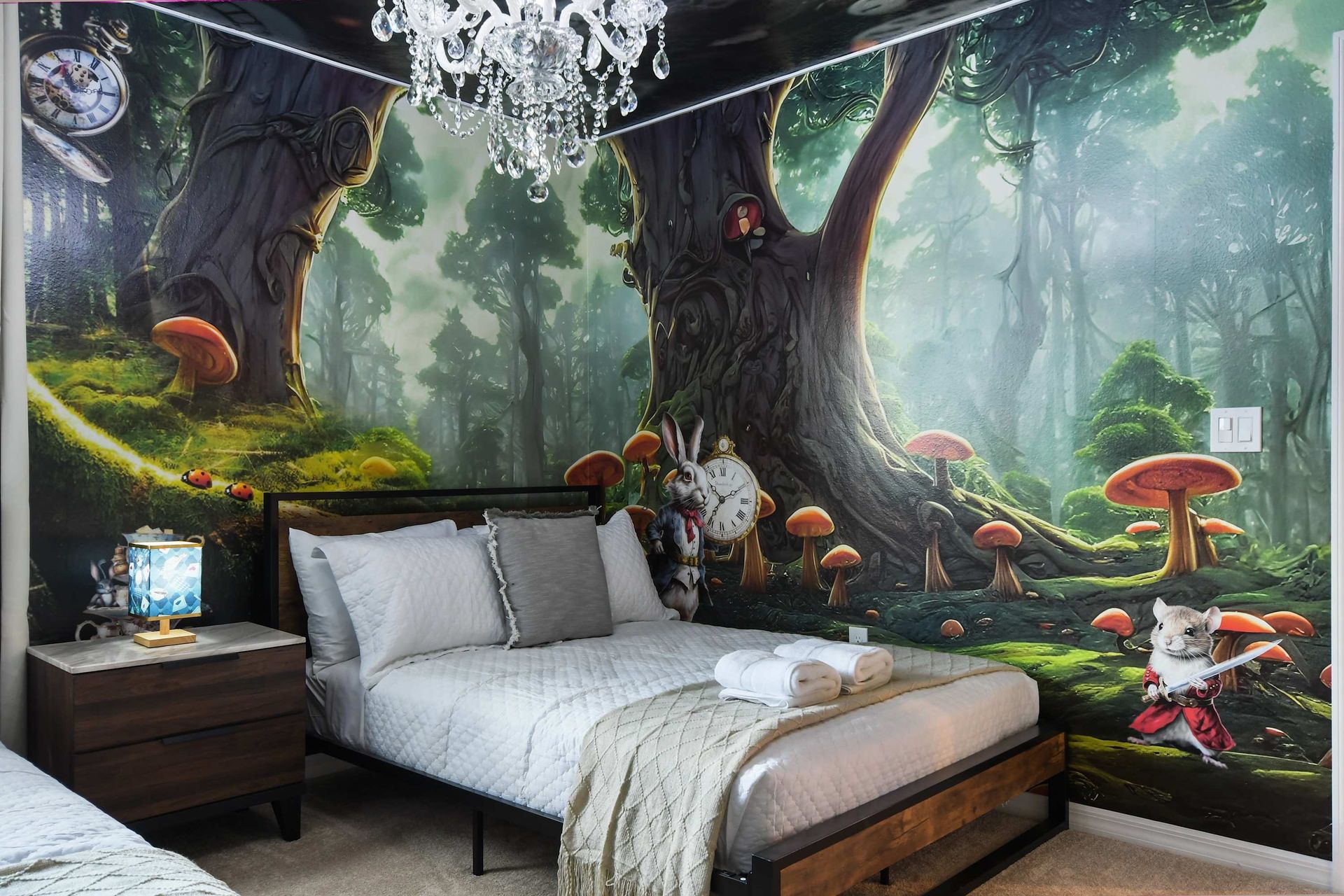 Enchanting forest-themed bedroom with twin beds, crystal chandelier, and storybook mural.
