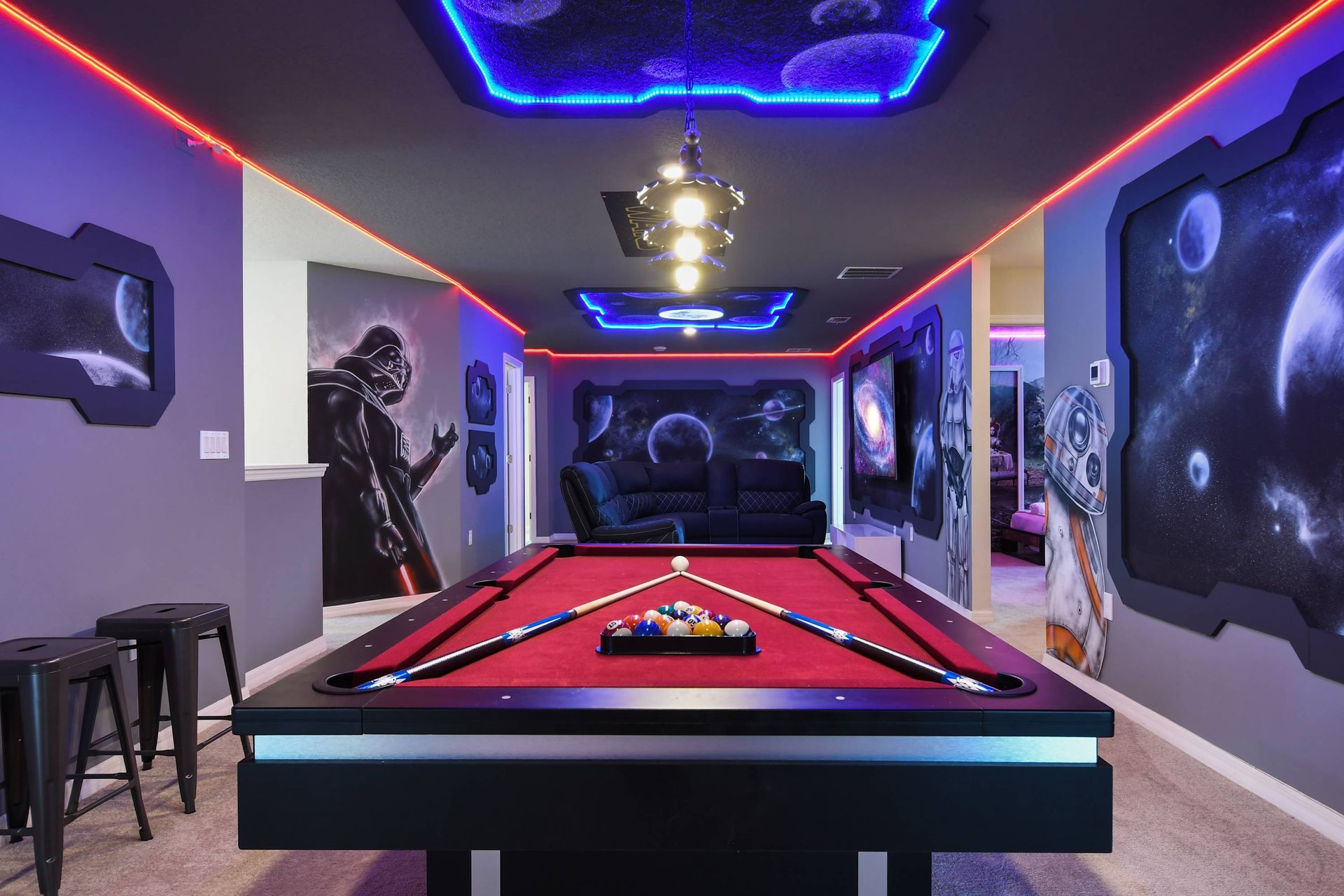 Futuristic Star Wars game room with glowing pool table, LED lights, and space murals.