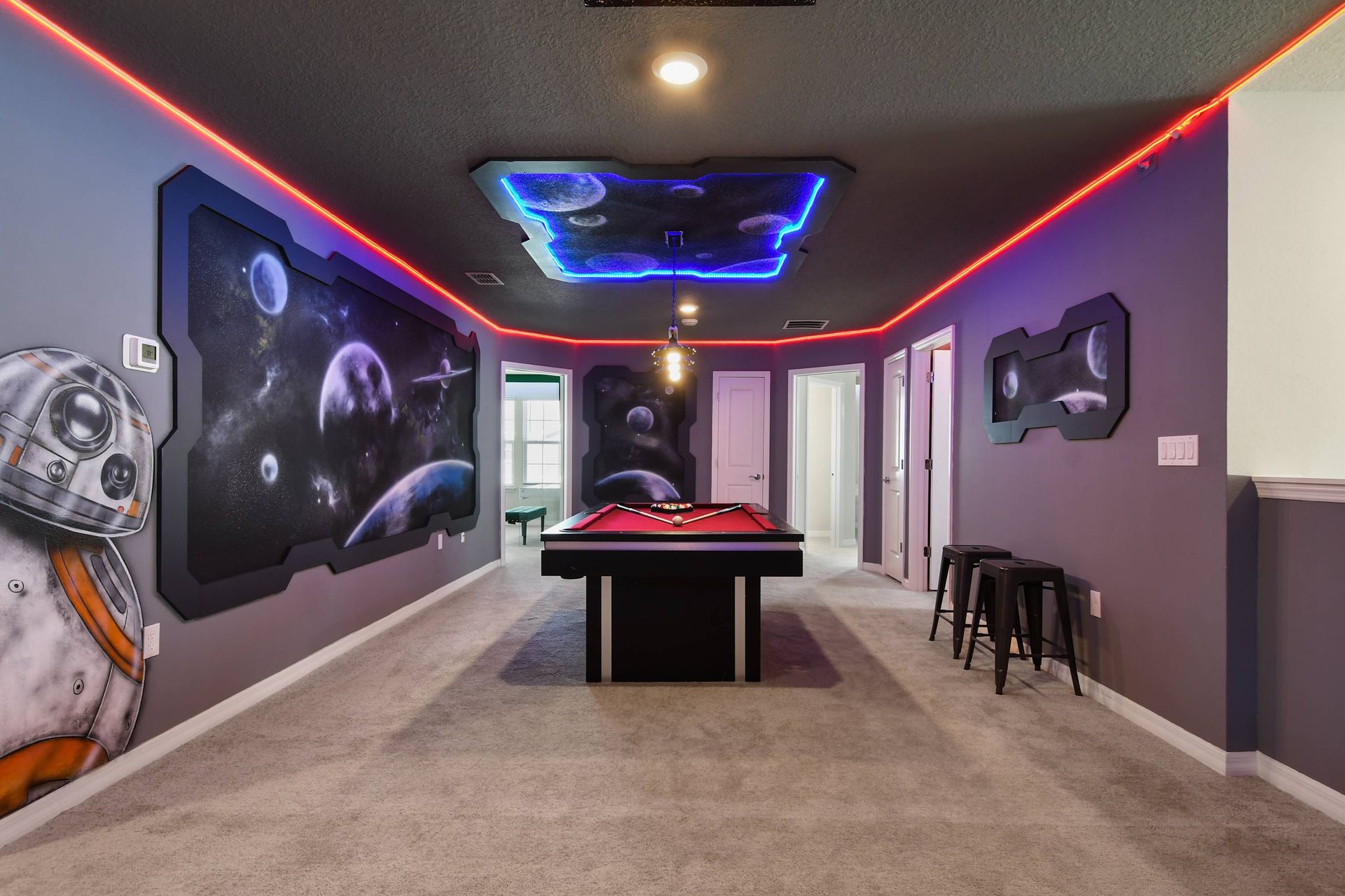 Space-themed game room with glowing LED lights, galactic art, and sleek pool table.