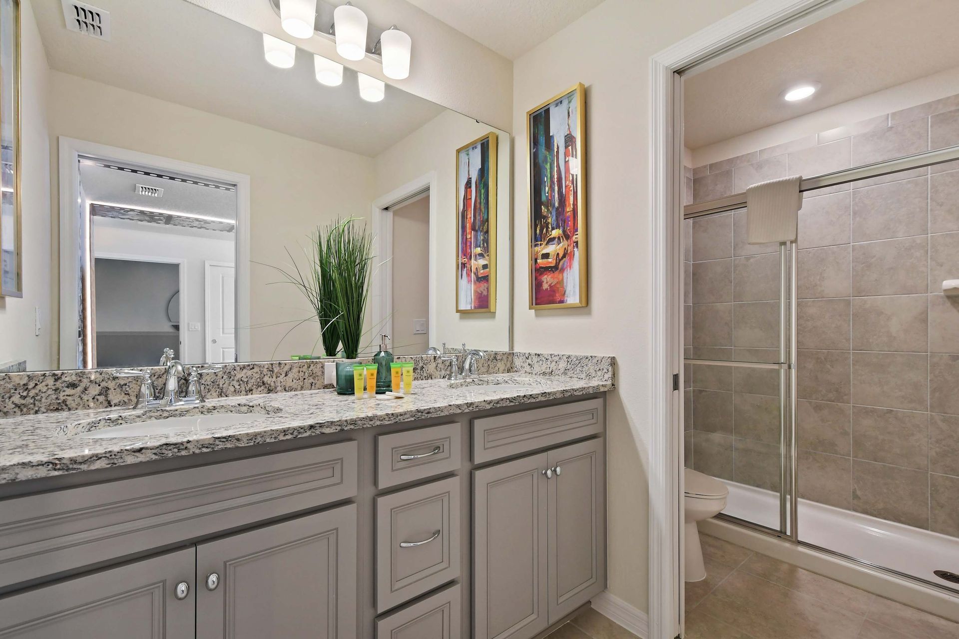 Stylish bath with dual vanities, granite counters, and sleek walk-in shower.