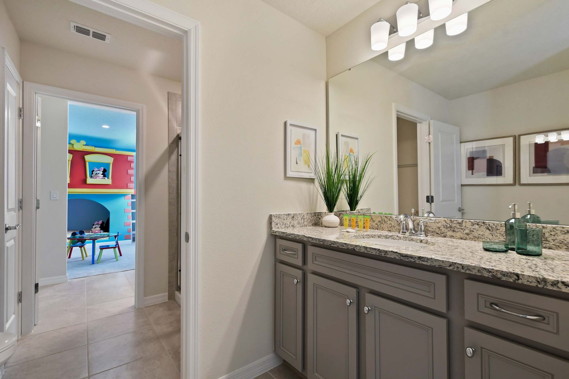Modern bathroom with granite vanity and walk-in shower, steps from themed kids' room.
