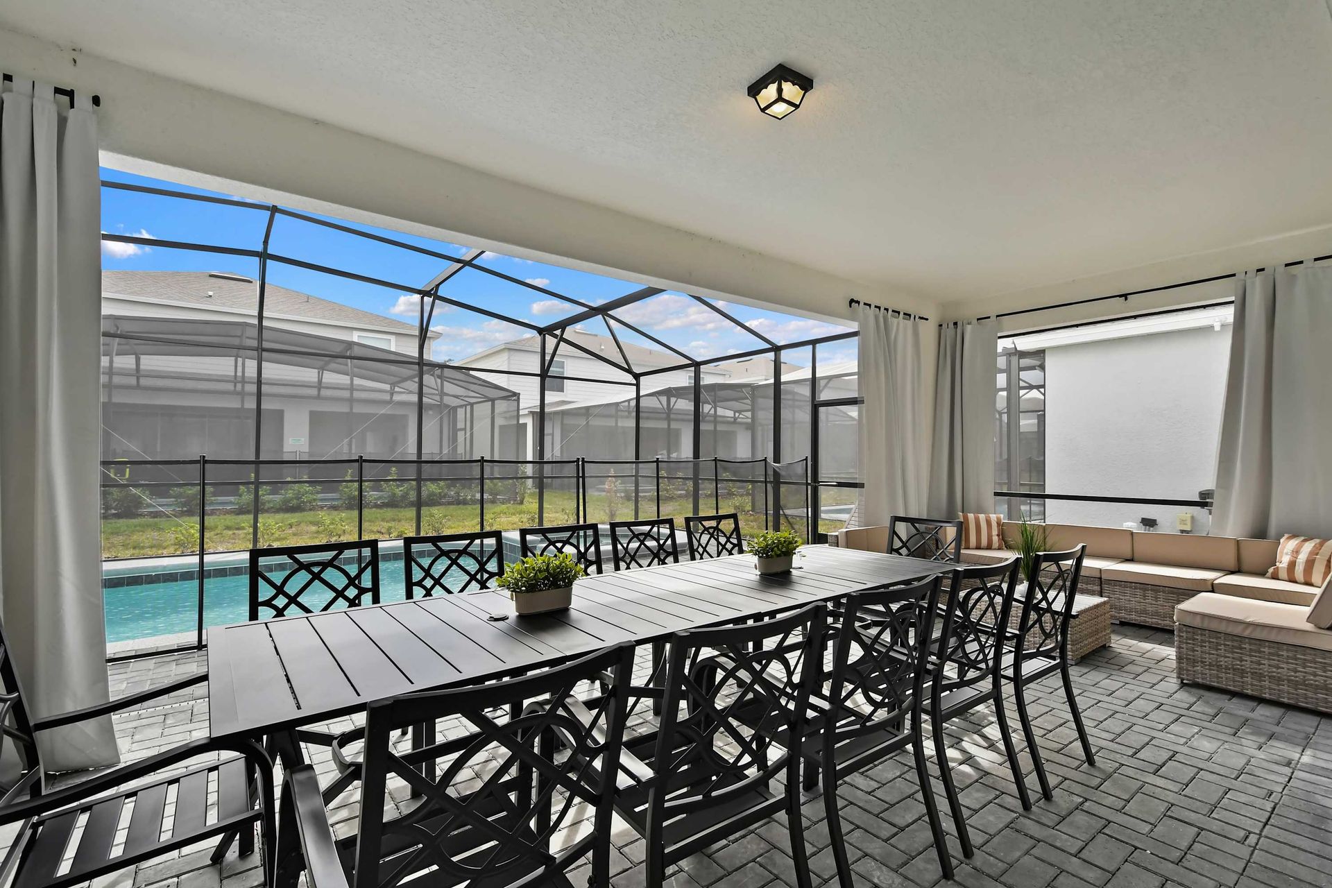 Spacious covered patio with dining for 12, cozy seating, and a view of the pool.