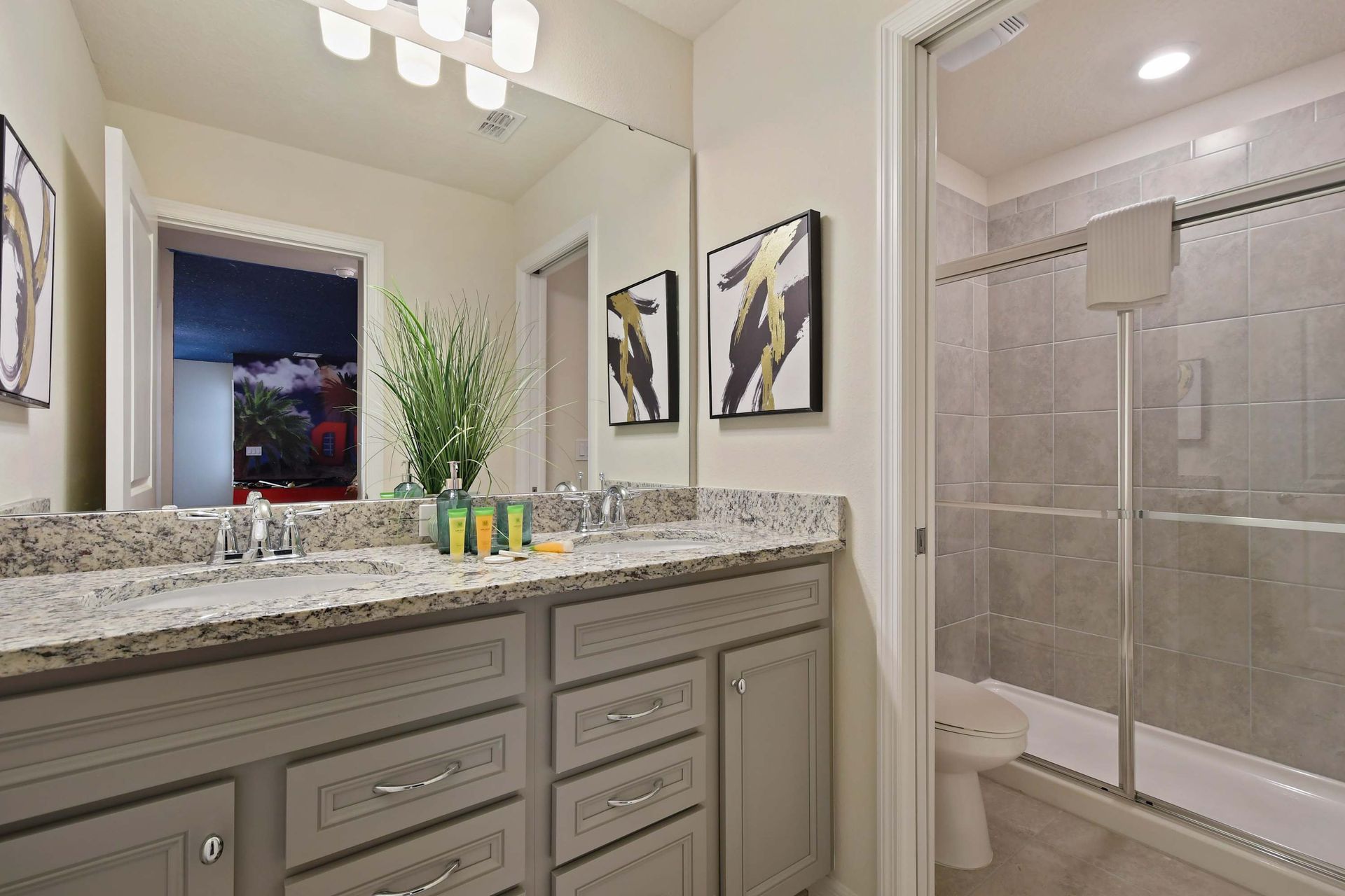 Stylish full bathroom with double sinks, granite counters, and sleek tile shower.