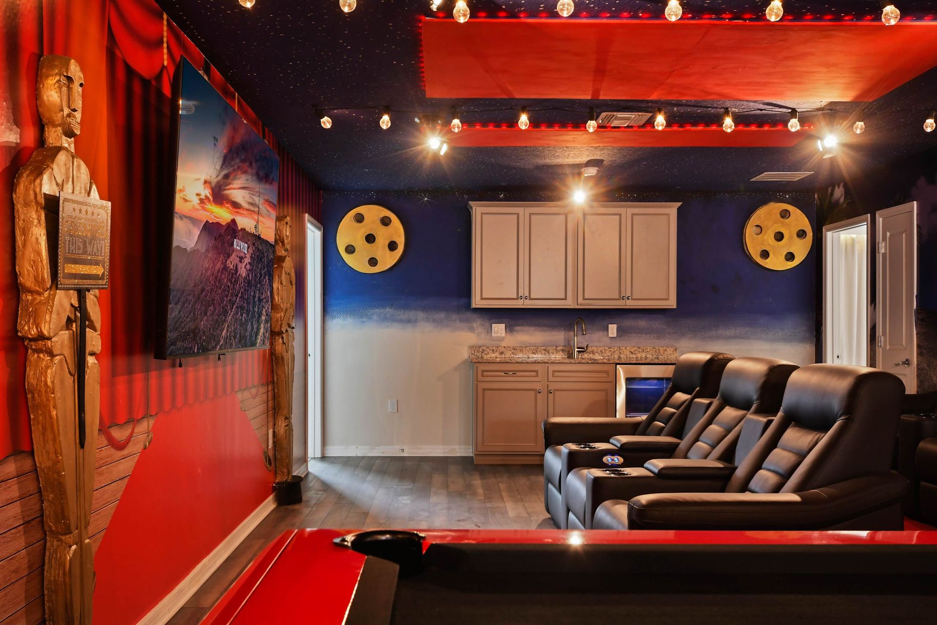 Cinematic lounge with leather recliners, wet bar, movie décor, and star-lit ceiling.