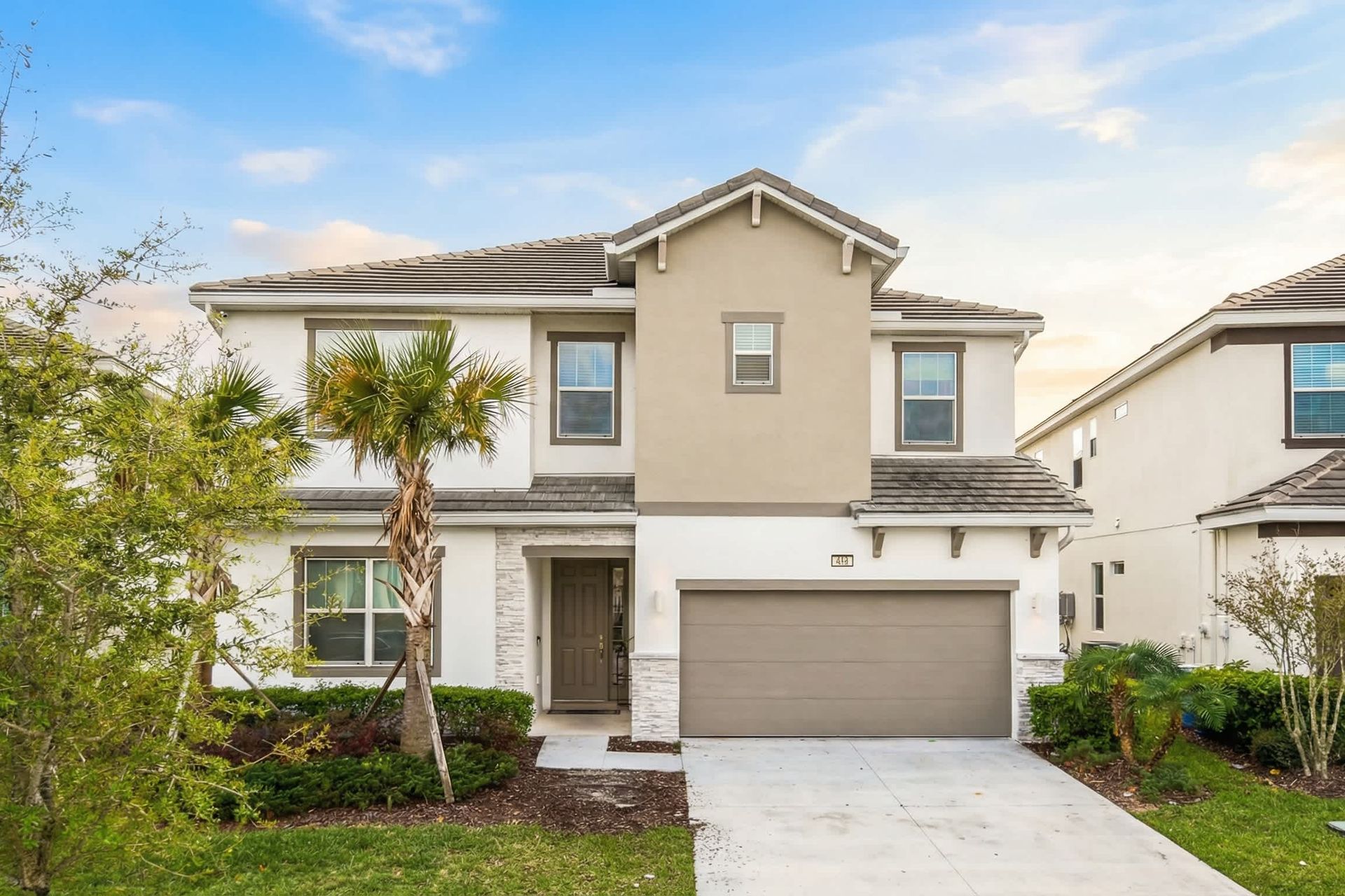 Modern family home with garage, palm trees, and bright curb appeal.
