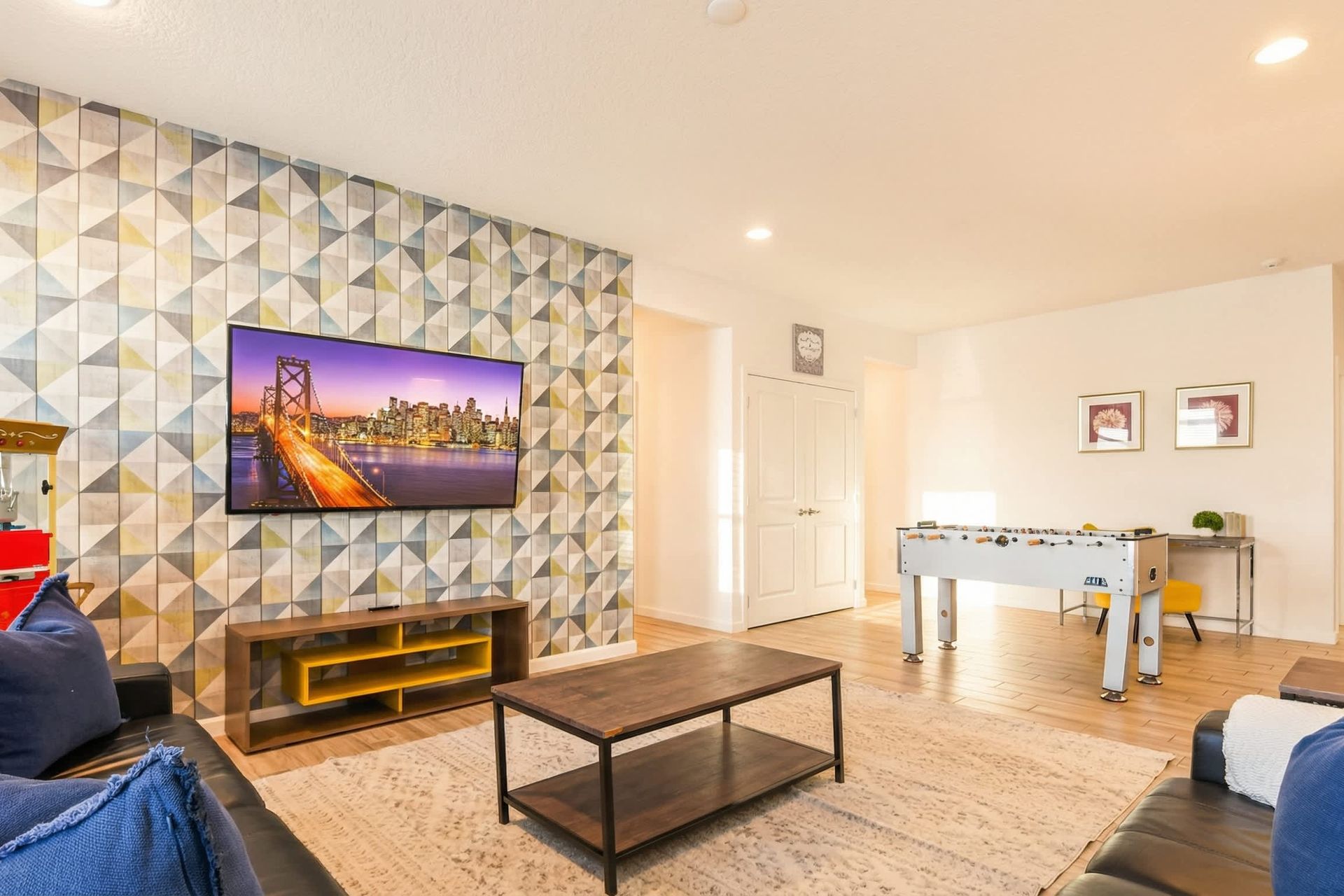 Vibrant game and media room with foosball, popcorn maker, and mounted TV.
