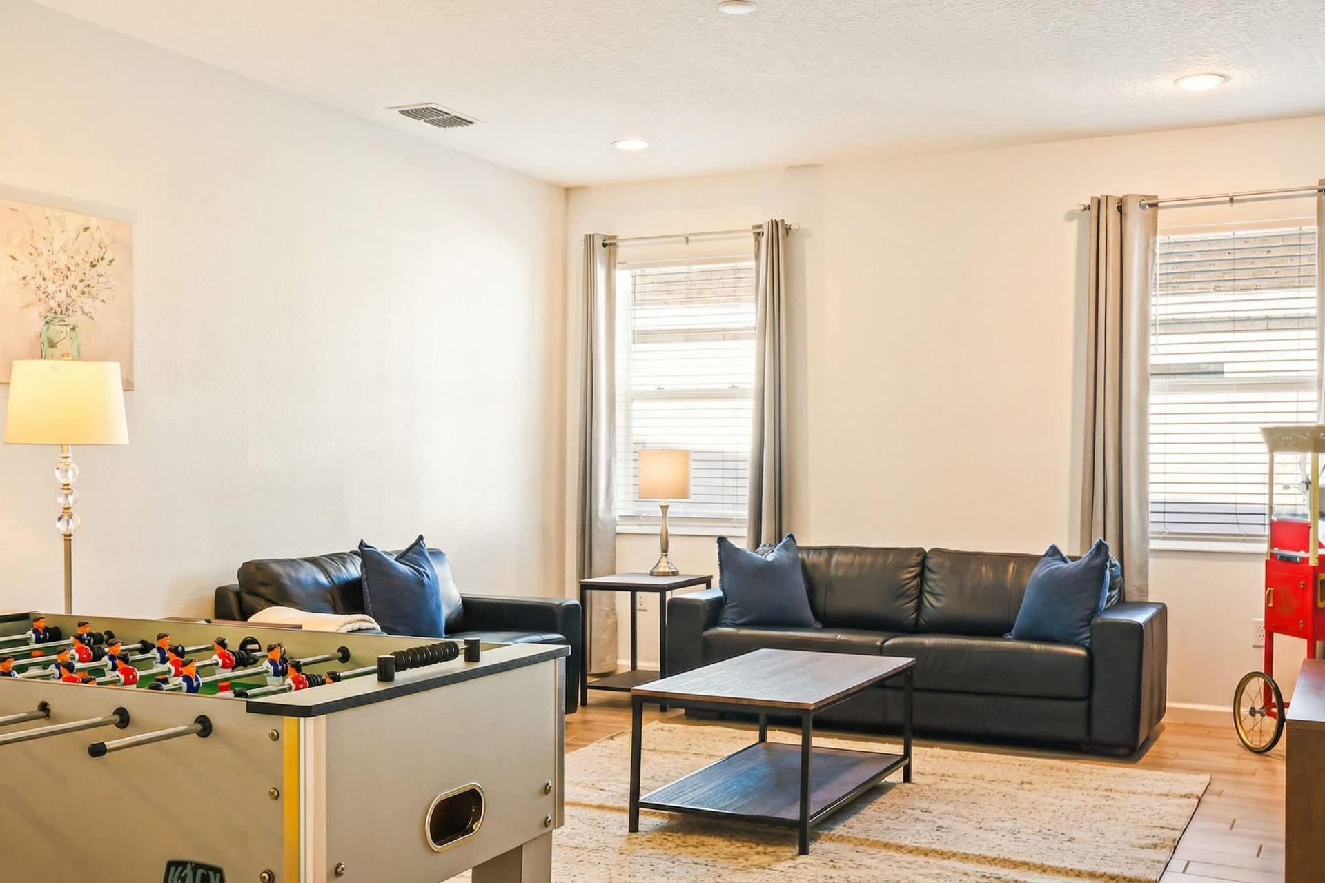 Entertainment lounge with foosball, leather sofas, popcorn machine, and smart TV.
