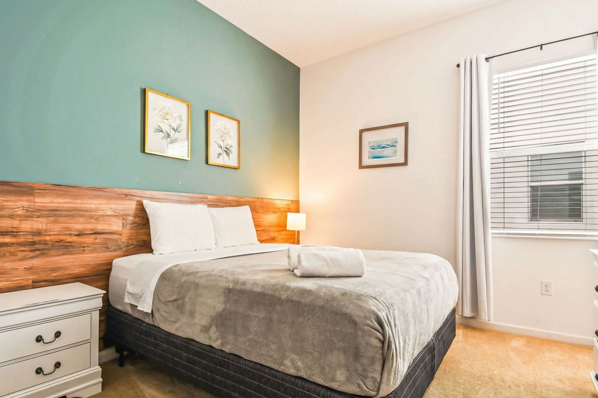 Serene bedroom with queen bed, green accent wall, and soft natural lighting.
