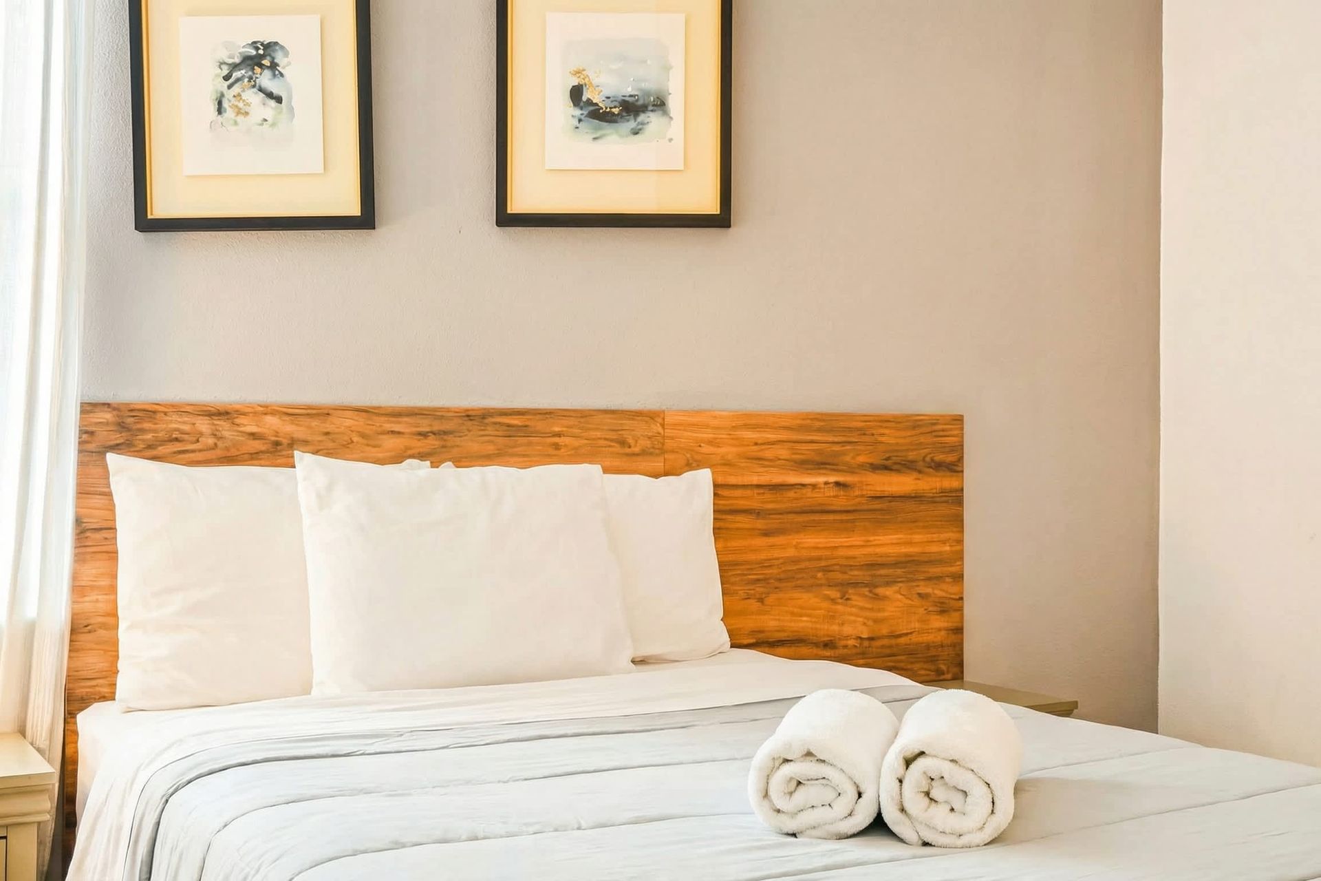 Cozy bed setup with wood headboard, soft linens, and calming wall art.

