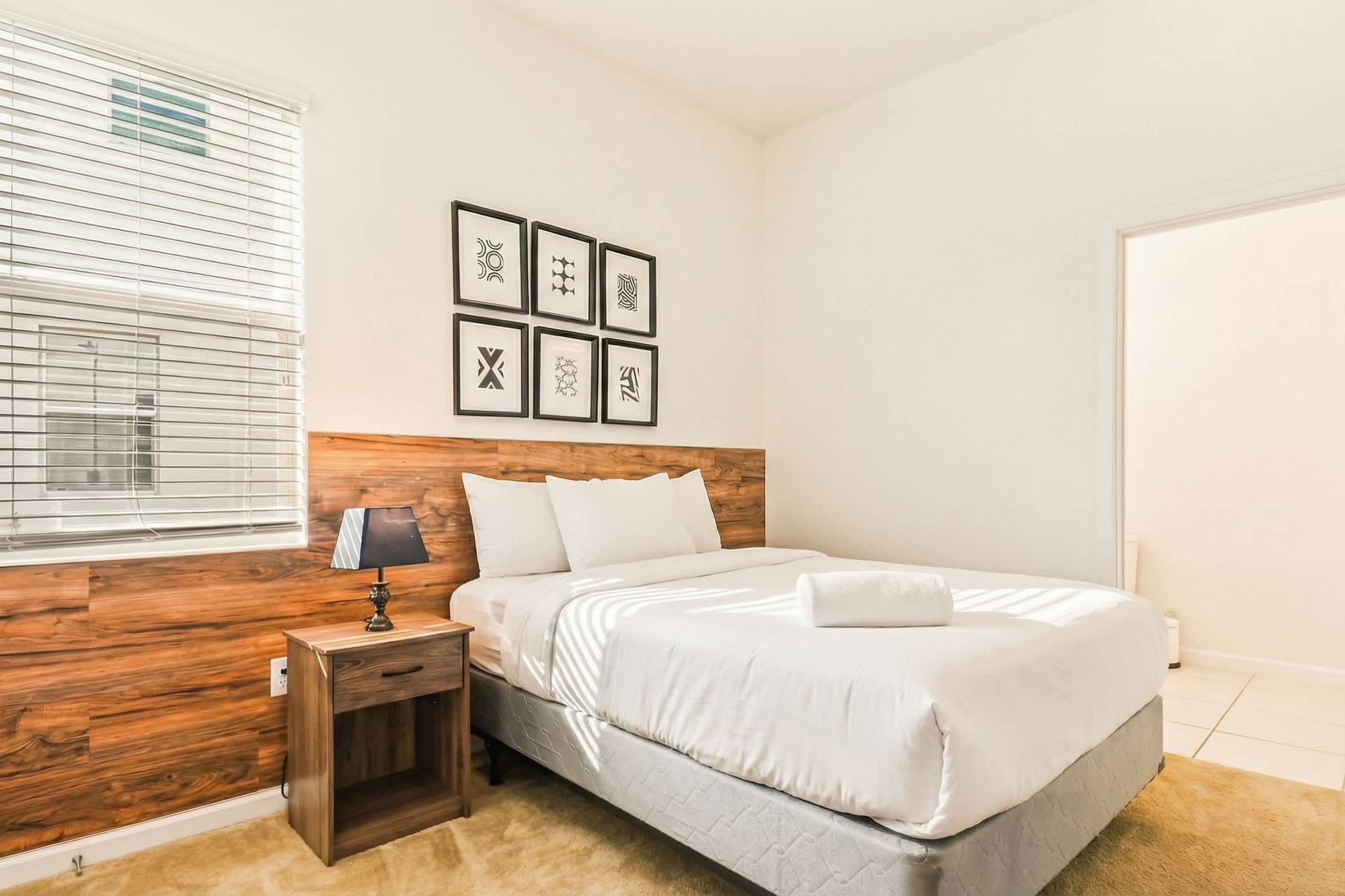 Bright minimalist bedroom with wood accents, modern art, and private bathroom.
