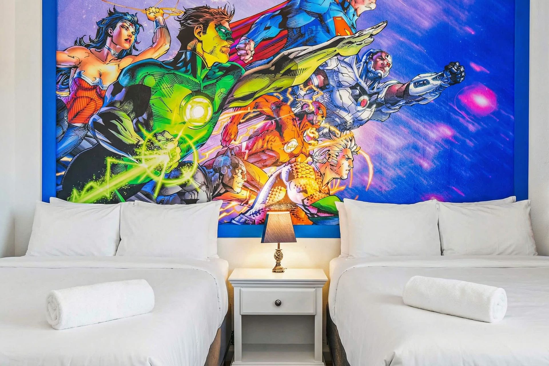 Vibrant superhero twin room with bold comic mural and bright blue bedding.
