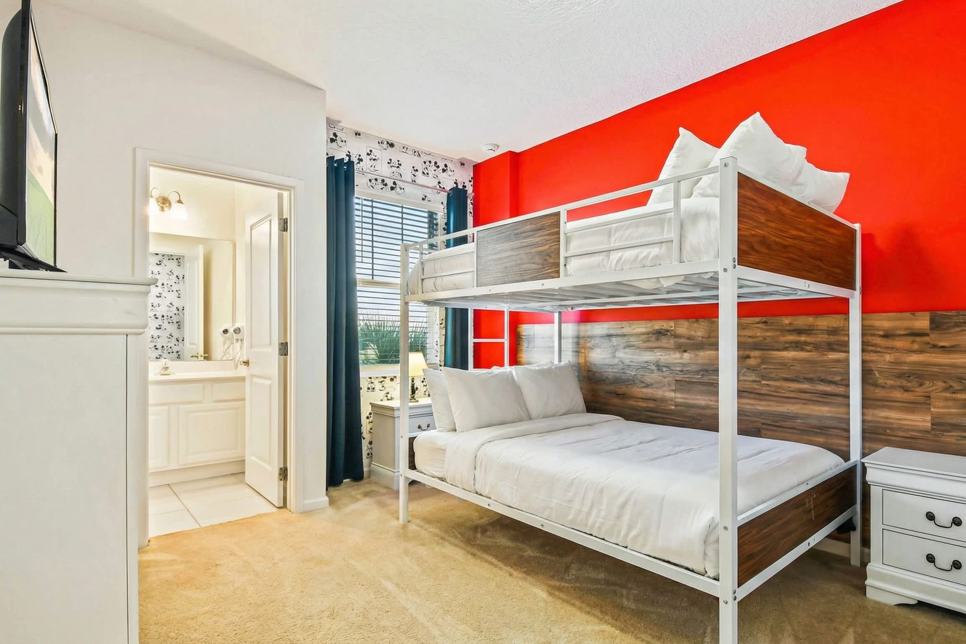 Colorful bunk room with bold red accent wall, purple bedding, and private bath.
