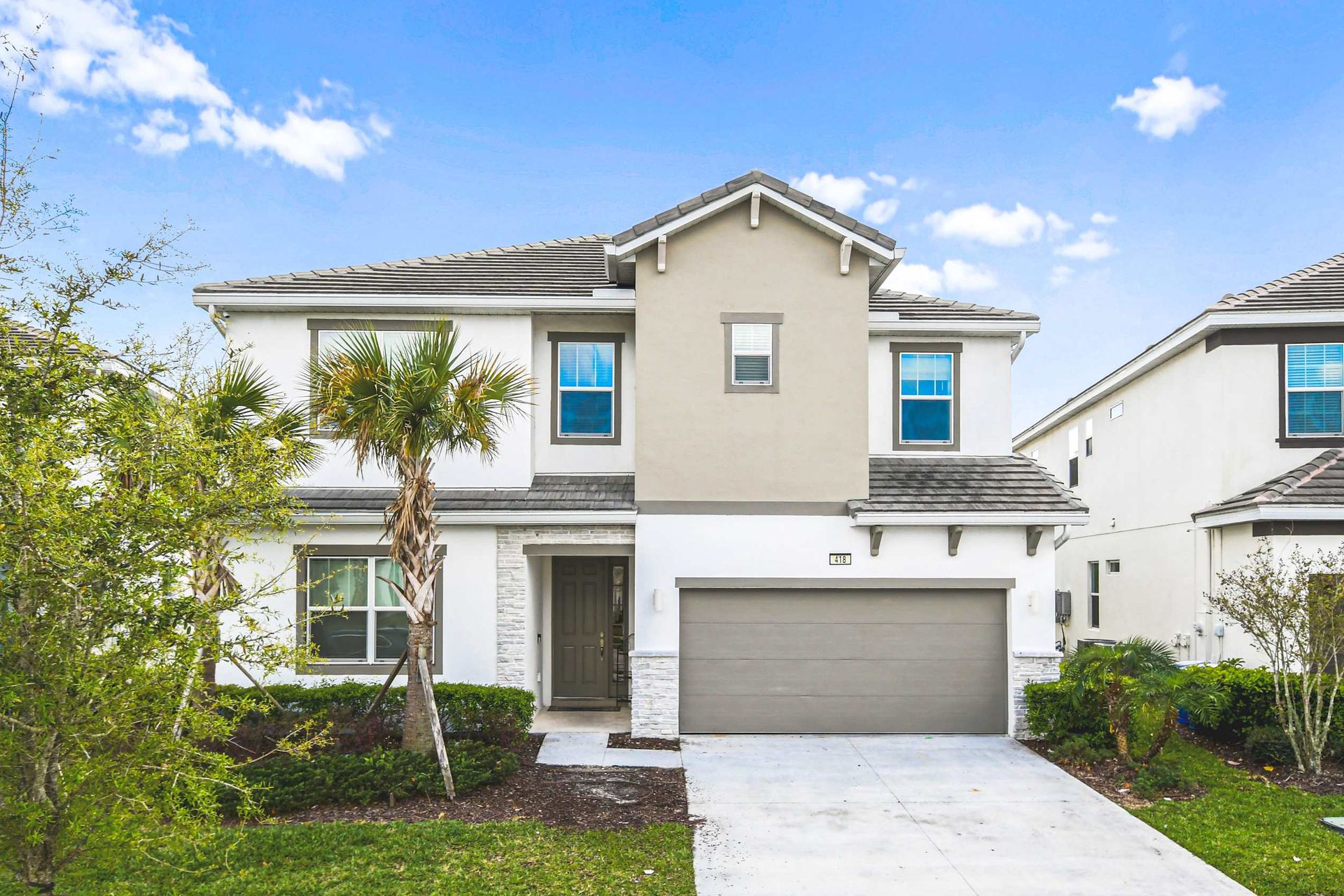 Modern family home with garage, palm trees, and bright curb appeal.

