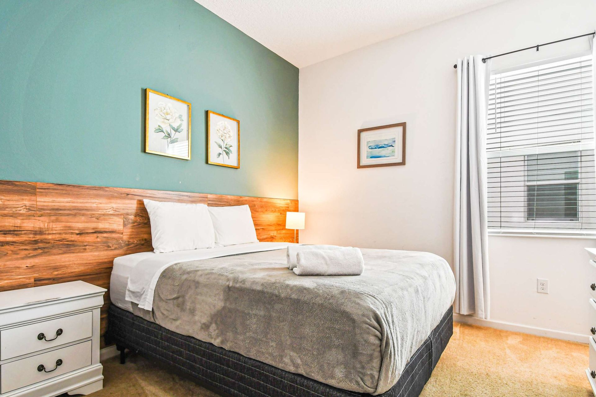 Serene bedroom with queen bed, green accent wall, and soft natural lighting.
