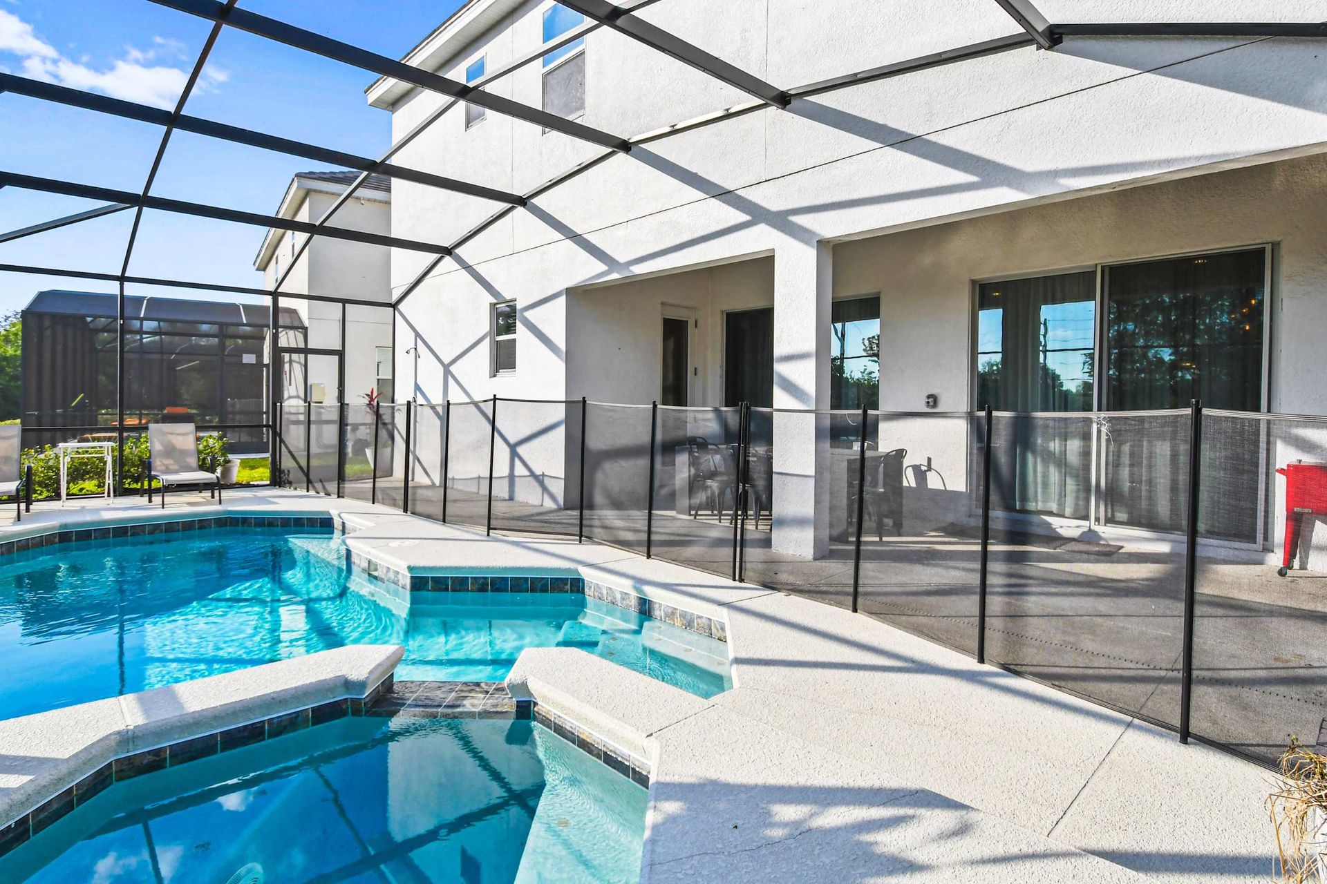 
Private screened pool and spa with loungers, patio seating, and dining area