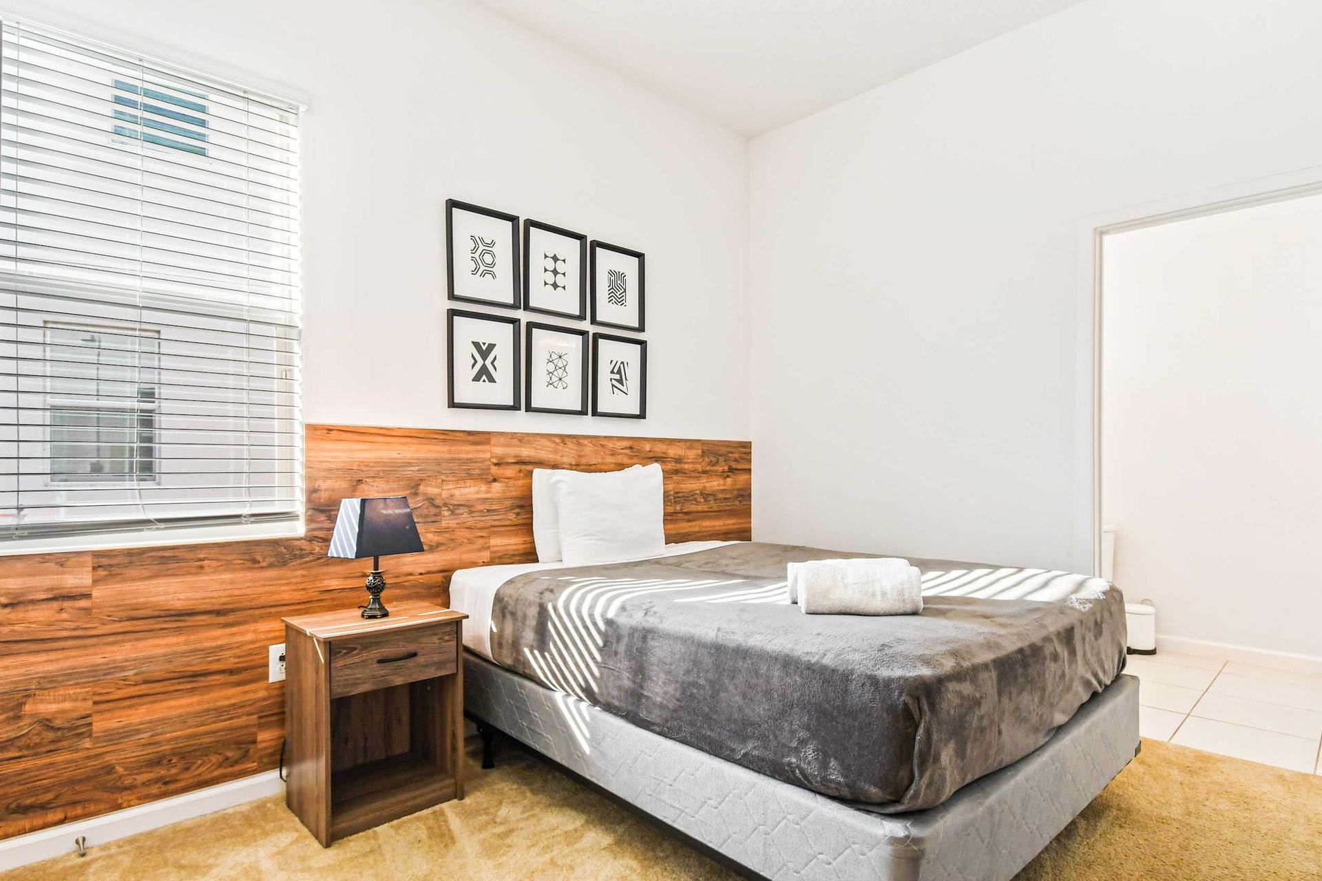 Bright minimalist bedroom with wood accents, modern art, and private bathroom.
