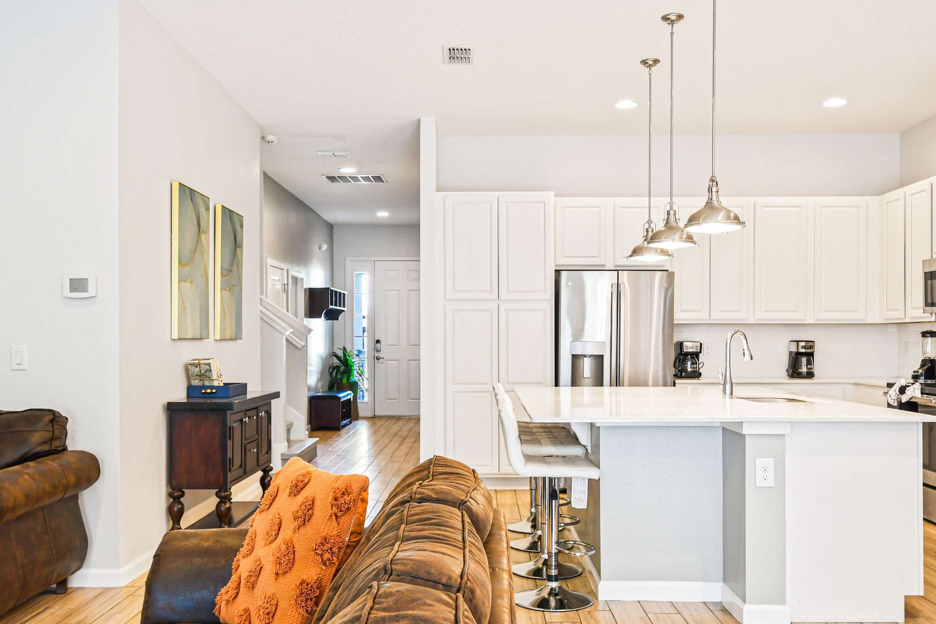 Sleek kitchen with stainless steel appliances, island seating, and bright design.
