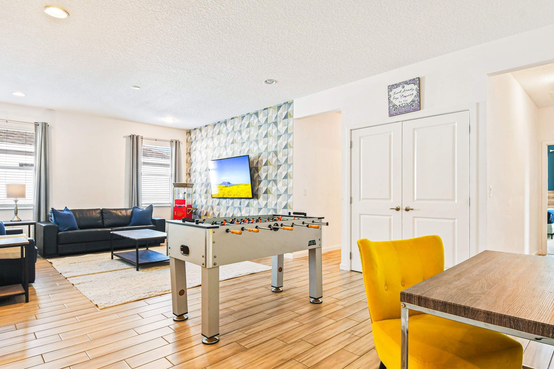 Game room lounge with foosball, TV, workspace, and bold modern accent wall.
