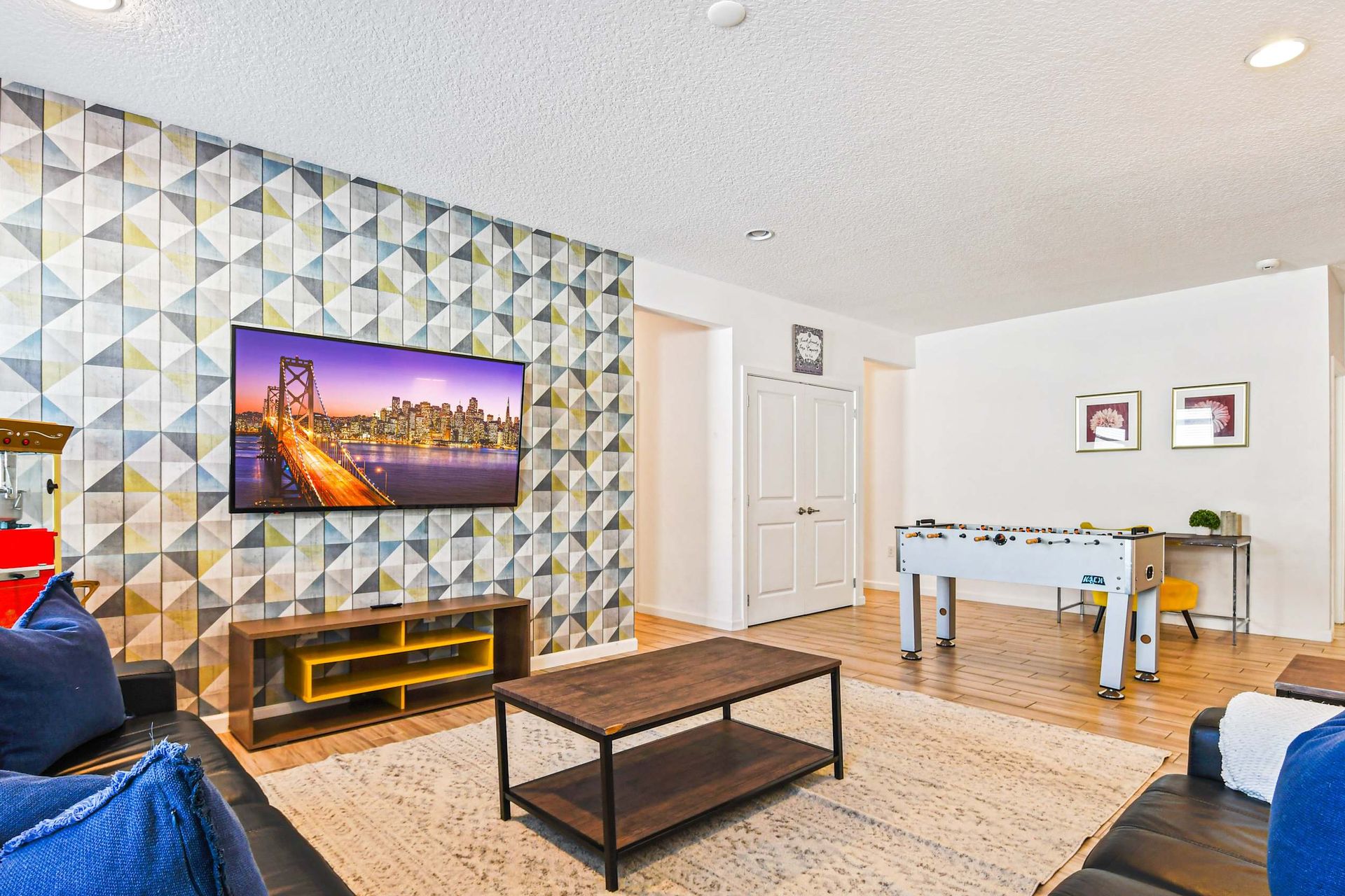 Vibrant game and media room with foosball, popcorn maker, and mounted TV.
