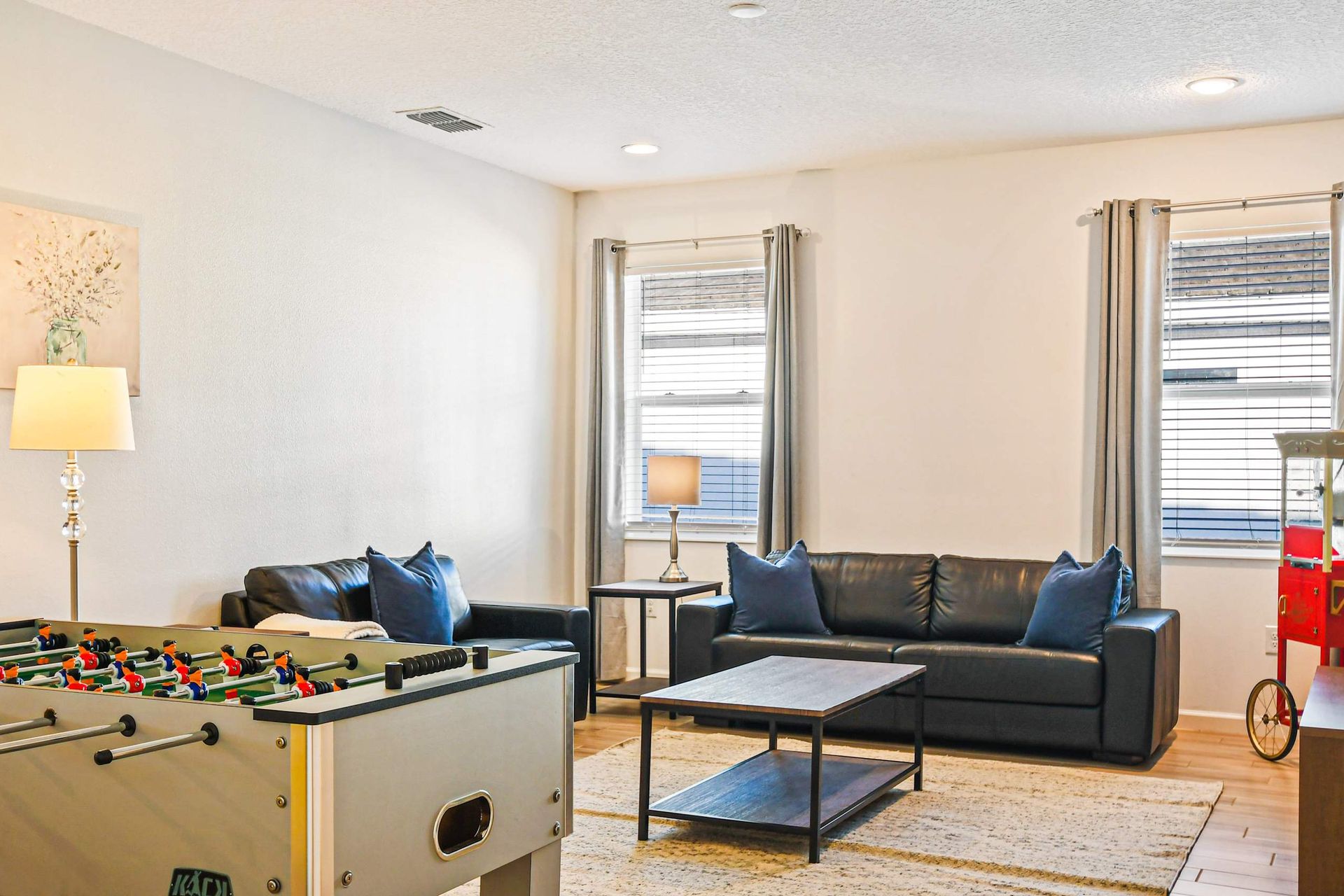 Entertainment lounge with foosball, leather sofas, popcorn machine, and smart TV.

