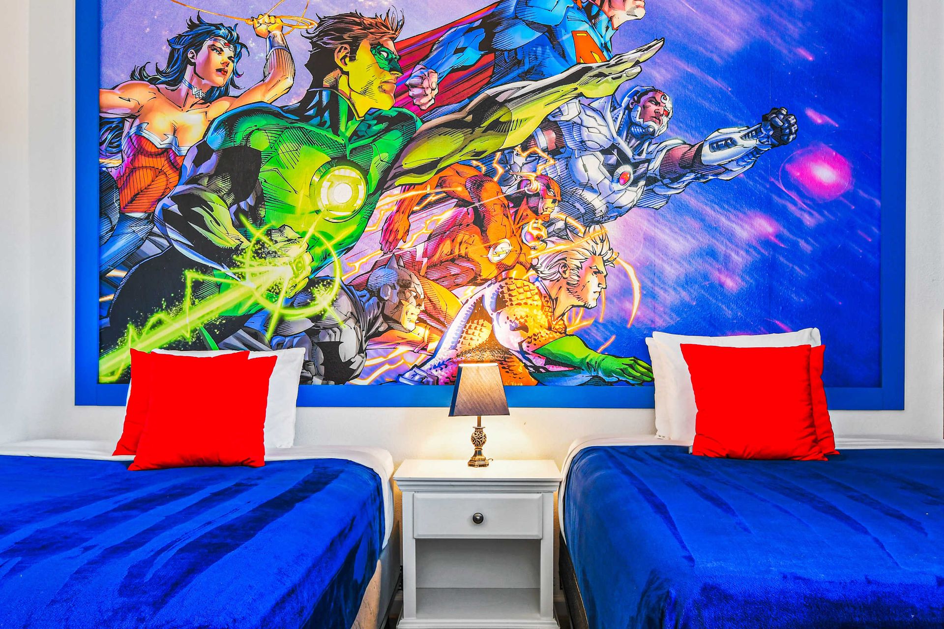 Vibrant superhero twin room with bold comic mural and bright blue bedding.
