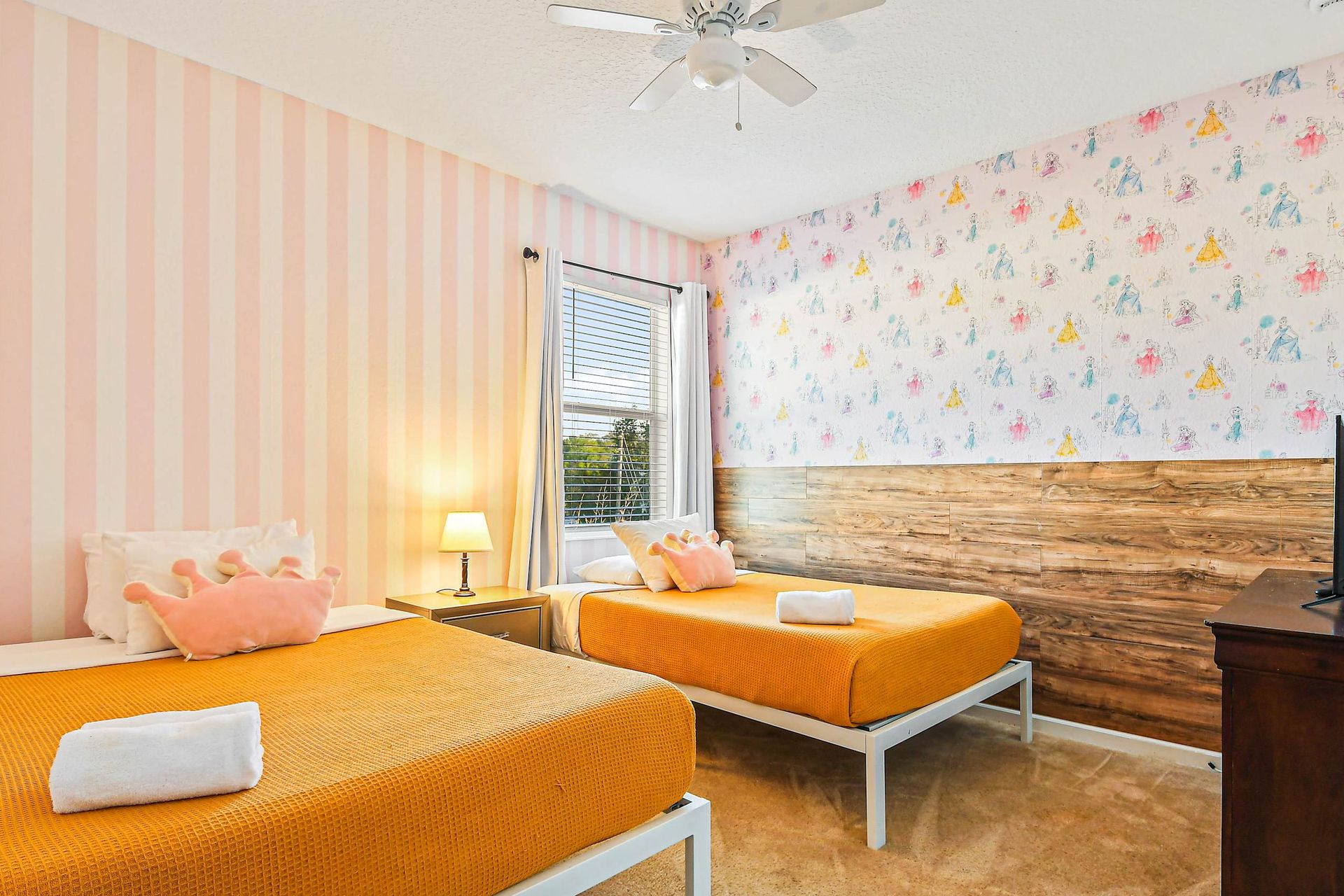 Charming princess-themed twin room with playful wallpaper and cozy bedding.
