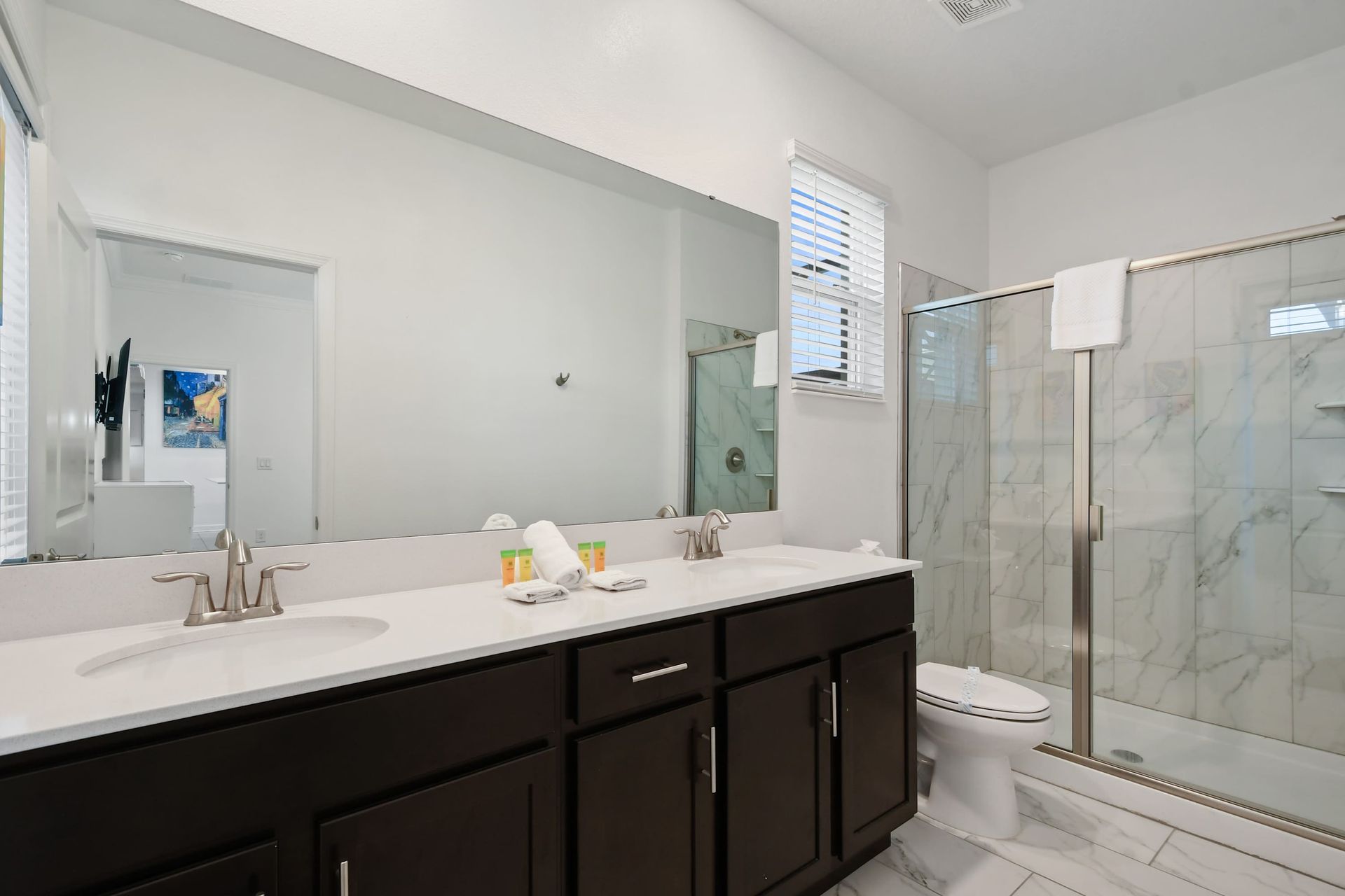 Spacious ensuite bath with double vanity, sleek walk-in shower, and marble tile.
