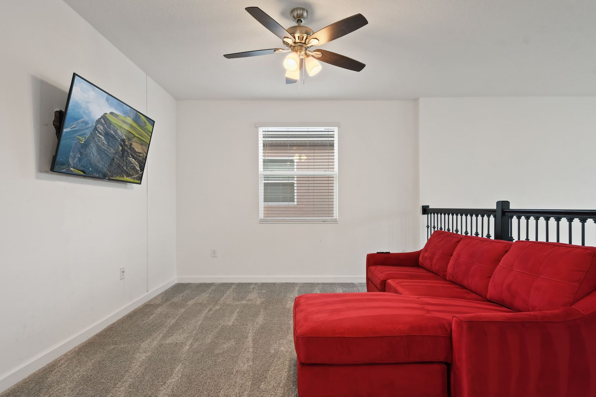 Cozy loft lounge with a bold red sectional and wall-mounted smart TV for streaming.