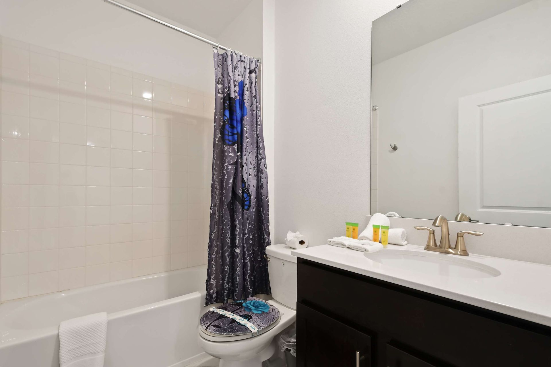 Cheerful full bathroom with playful decor, fresh linens, and a shower-tub combo.