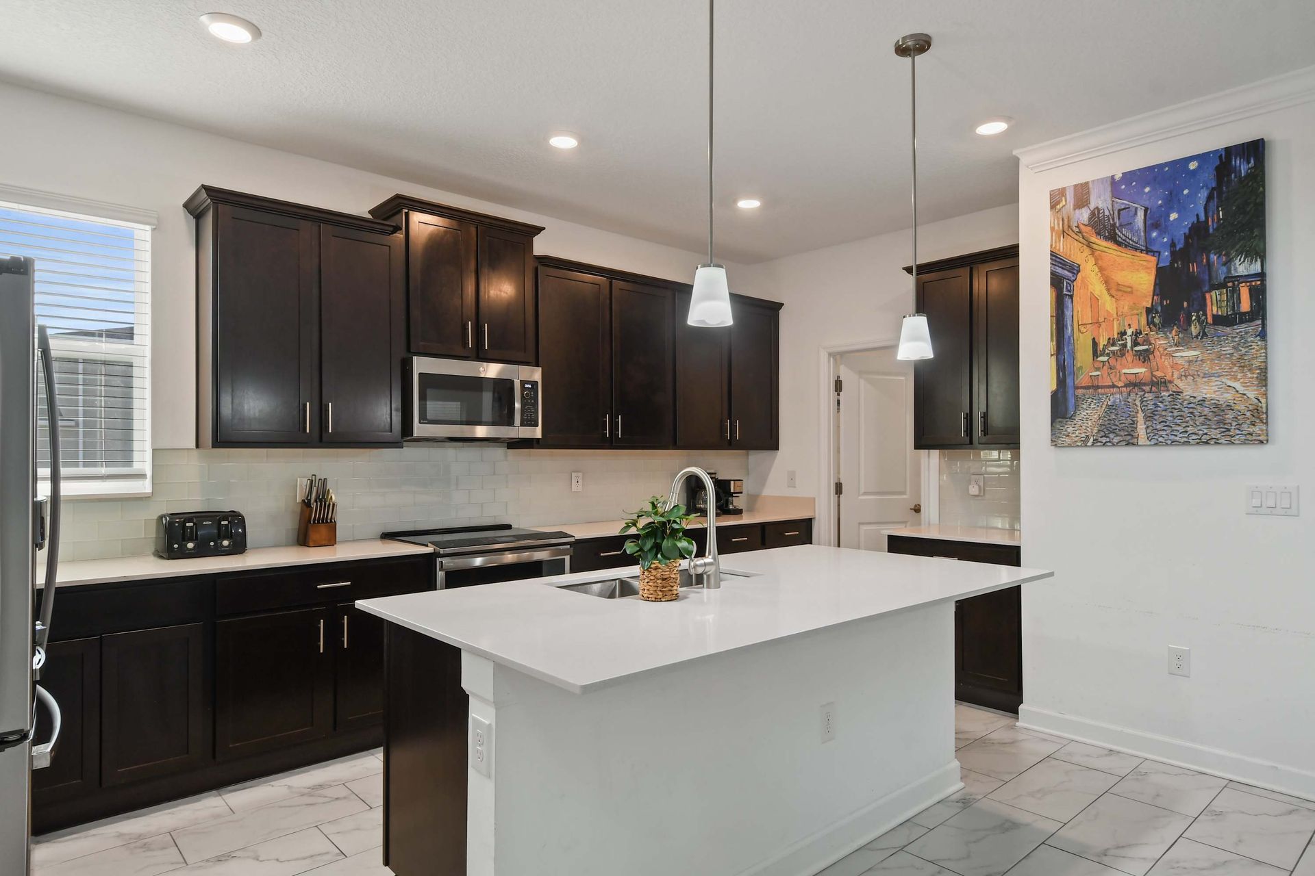 Modern kitchen with sleek dark cabinetry, quartz island, and stainless steel appliances.
