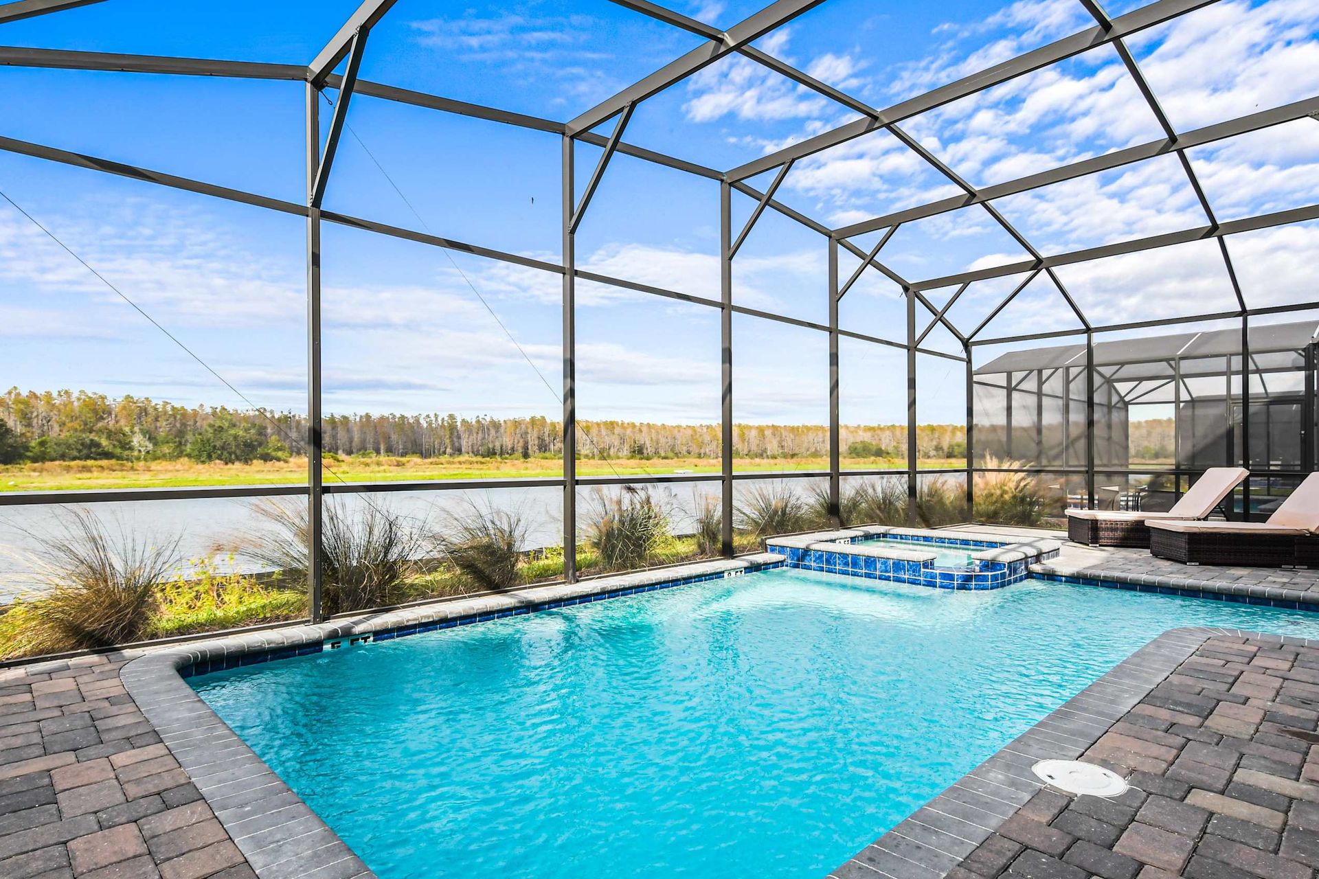 Stunning screened pool and spa with serene lake views and sunny lounge space.