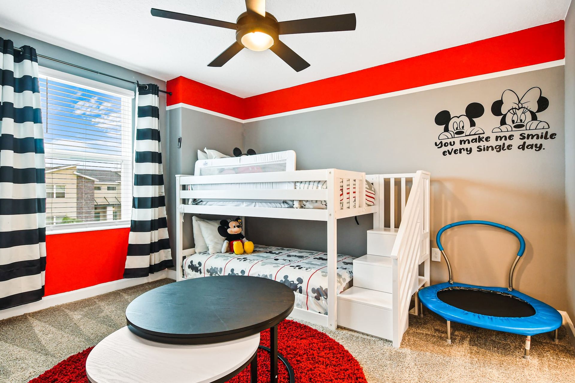 Fun-filled kids' room with bunk beds, trampoline, and cheerful Disney decor.
