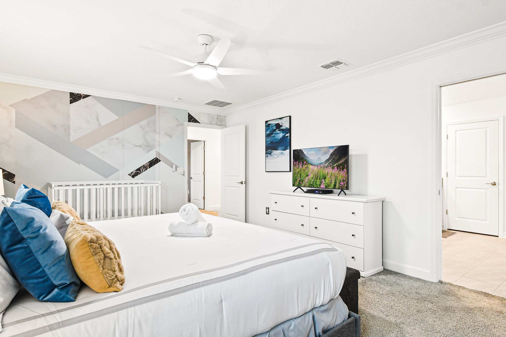 Bright and spacious bedroom with king bed, smart TV, and modern accent wall.