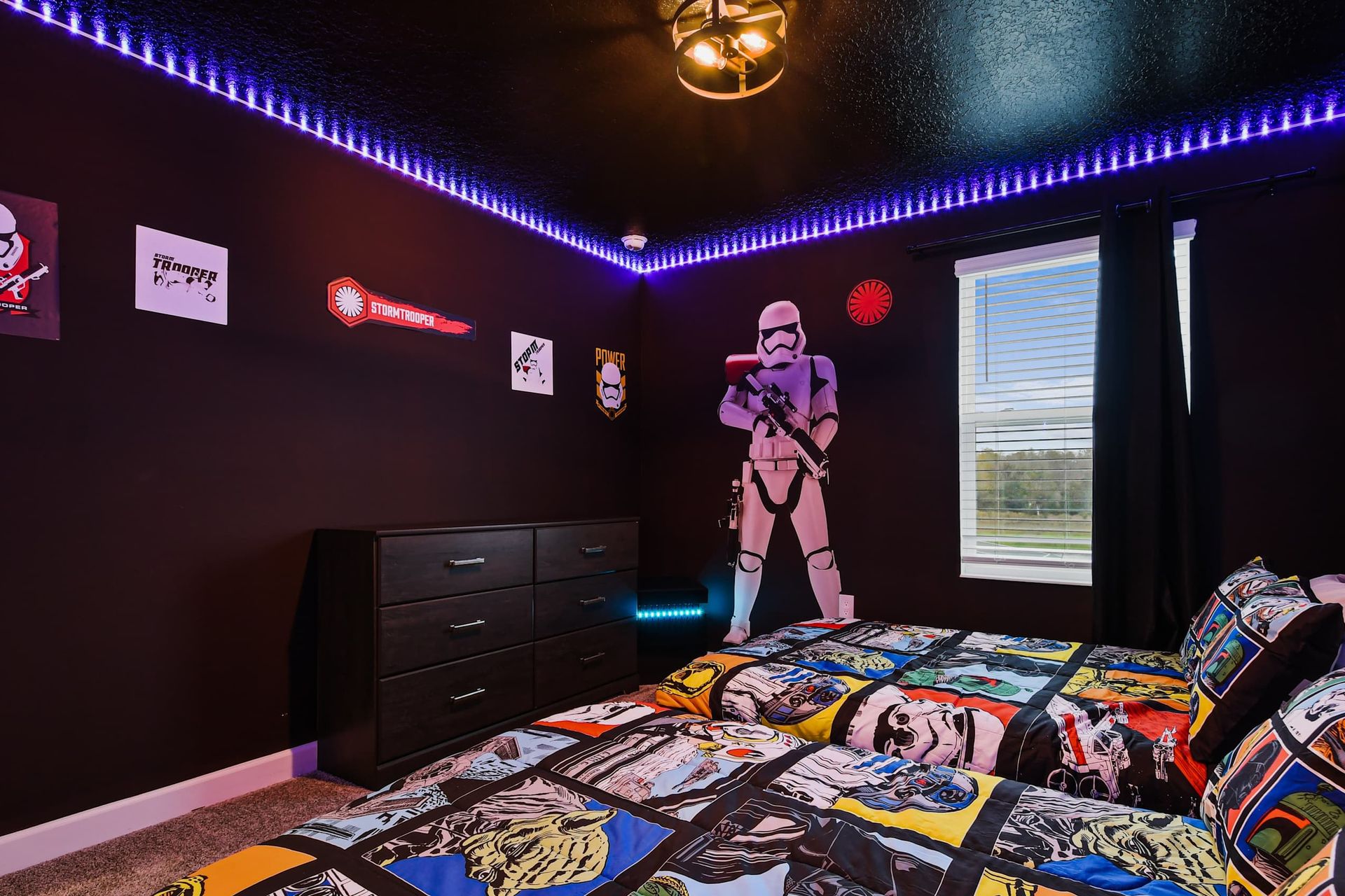 Galactic-themed bedroom with twin beds, glowing LED lights, and bold wall art.