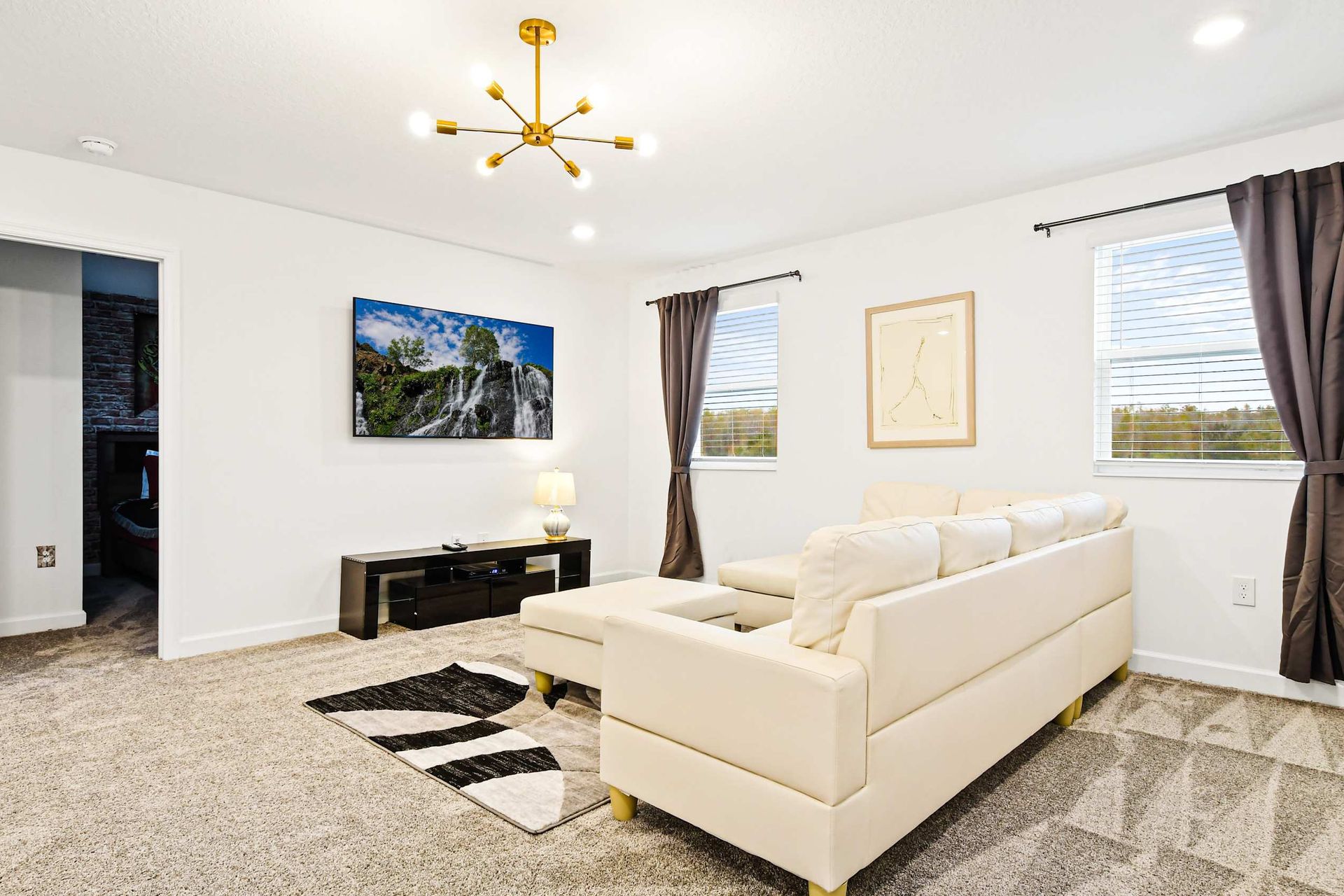 Cozy upstairs media room with large TV, comfy sectional, and nature views.