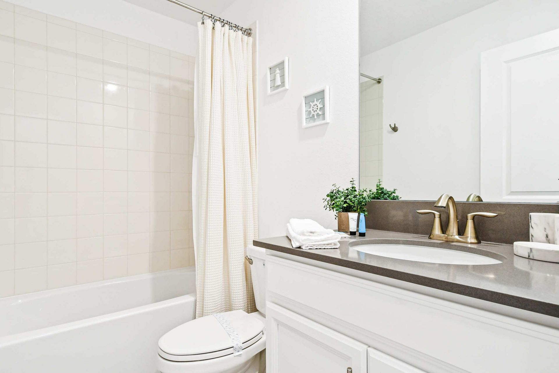 Modern full bathroom with sleek vanity, bright decor, and a relaxing shower-tub combo.